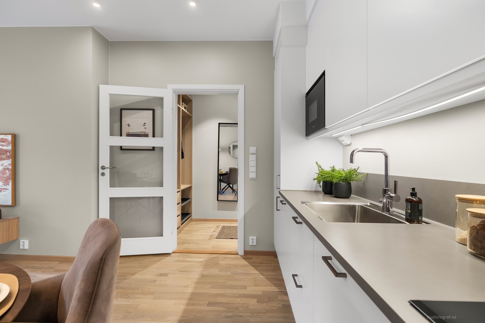 I enden av entréen er det en praktisk dør med glassfelt inn til kjøkkenet, noe som regulerer både eventuell støy og temperatur. Galleribilde