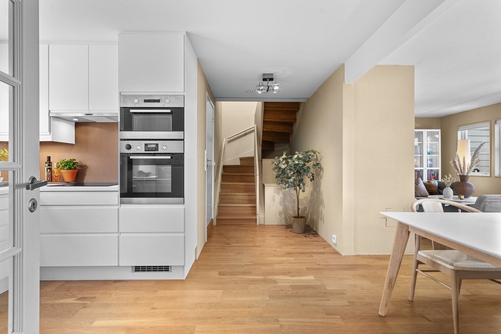 Et sosialt rom med flere soner og etablert plass til spisebord i tilknytning til kjøkkenet. Galleribilde