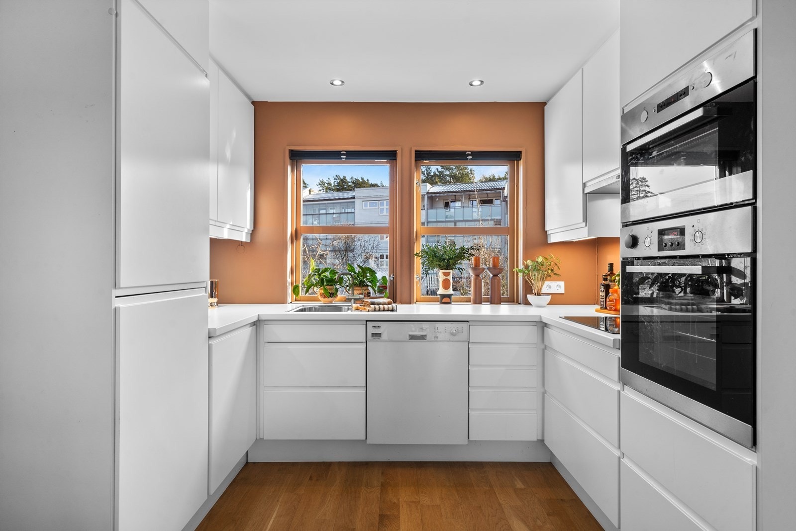 Et stilrent kjøkken i åpen løsning mot stuen fra ca. 2011. Hvitevarer som induksjonstopp, oppvaskmaskin, kjøl/frys, stekeovn og micro. Galleribilde