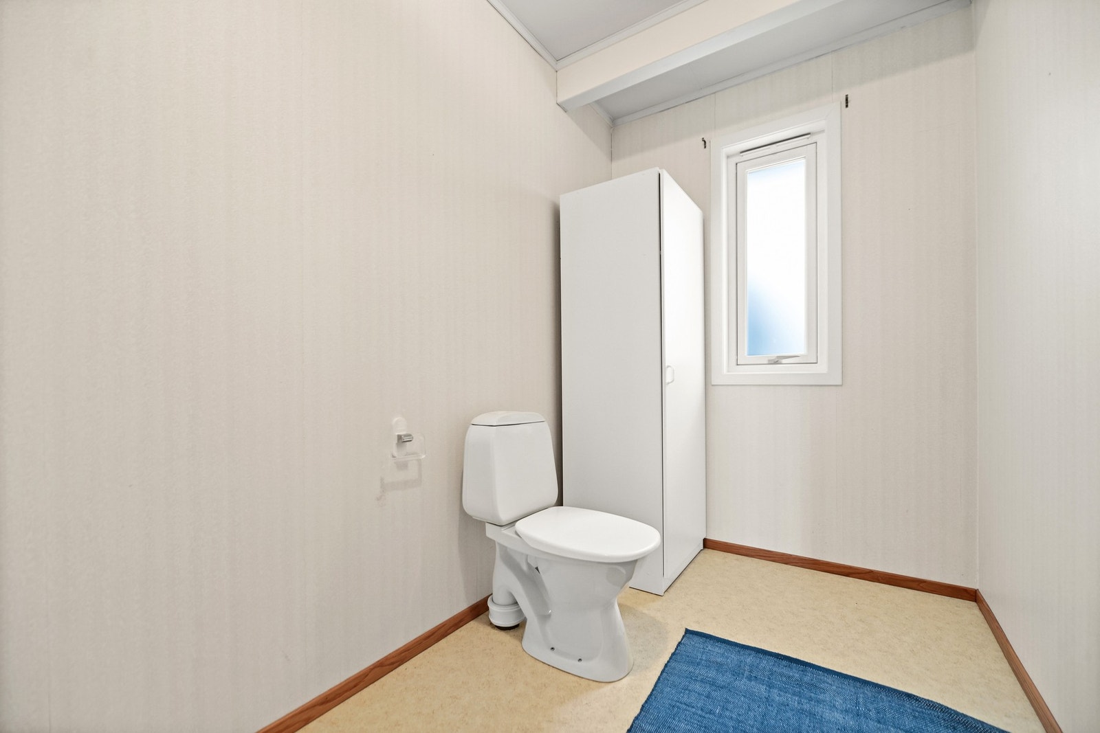 Badet har toalett, skap og vindu som gir naturlig lys. Veggene er lyse og gulvet har belegg. Galleribilde