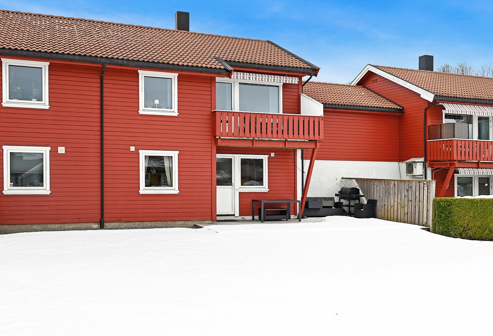 Hagen foran boligen er snødekt og gir et rent og pent inntrykk. Den har en flat og åpen flate, perfekt for ulike uteaktiviteter. En hekk gir privatliv og skjerming mot naboer, og det finnes en liten uteplass med bord og grillmuligheter. Galleribilde