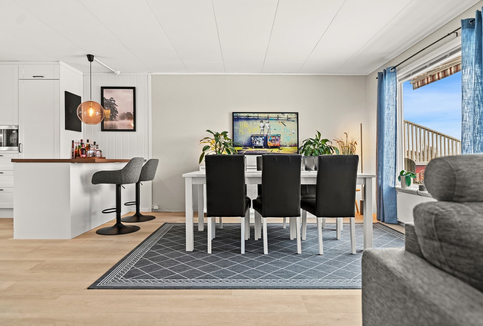 Lys og romslig stue med åpen kjøkkenløsning og spiseplass ved vinduet. Galleribilde