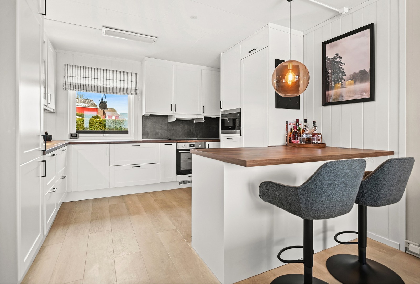 Moderne kjøkken med hvite skap, integrerte hvitevarer og romslig benkeplate. Store vinduer gir godt med naturlig lys. Galleribilde