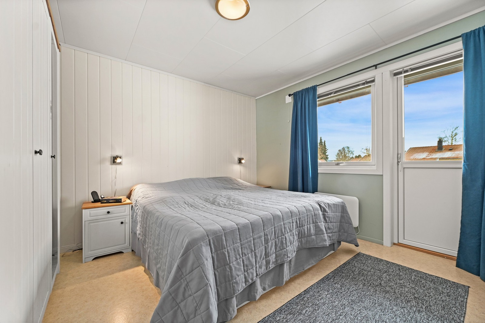 Soverom med lyse vegger, stort vindu og enkel belysning. Galleribilde