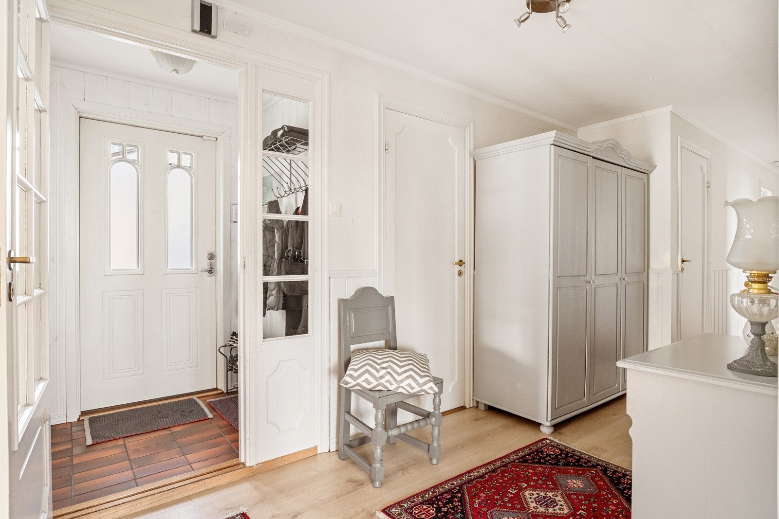 Boligen ønsker deg velkommen inn i en entré med flislagt gulv og lyse vegger. Galleribilde