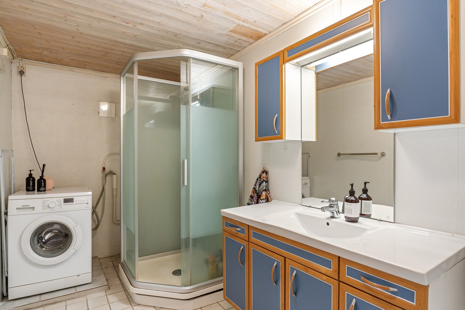 I våtrommet i kjelleren er det oppført en skillevegg som deler våtrommet i to soner: én benyttet som bad og den andre som vaskerom. Våtrommet er modent for modernisering. Galleribilde