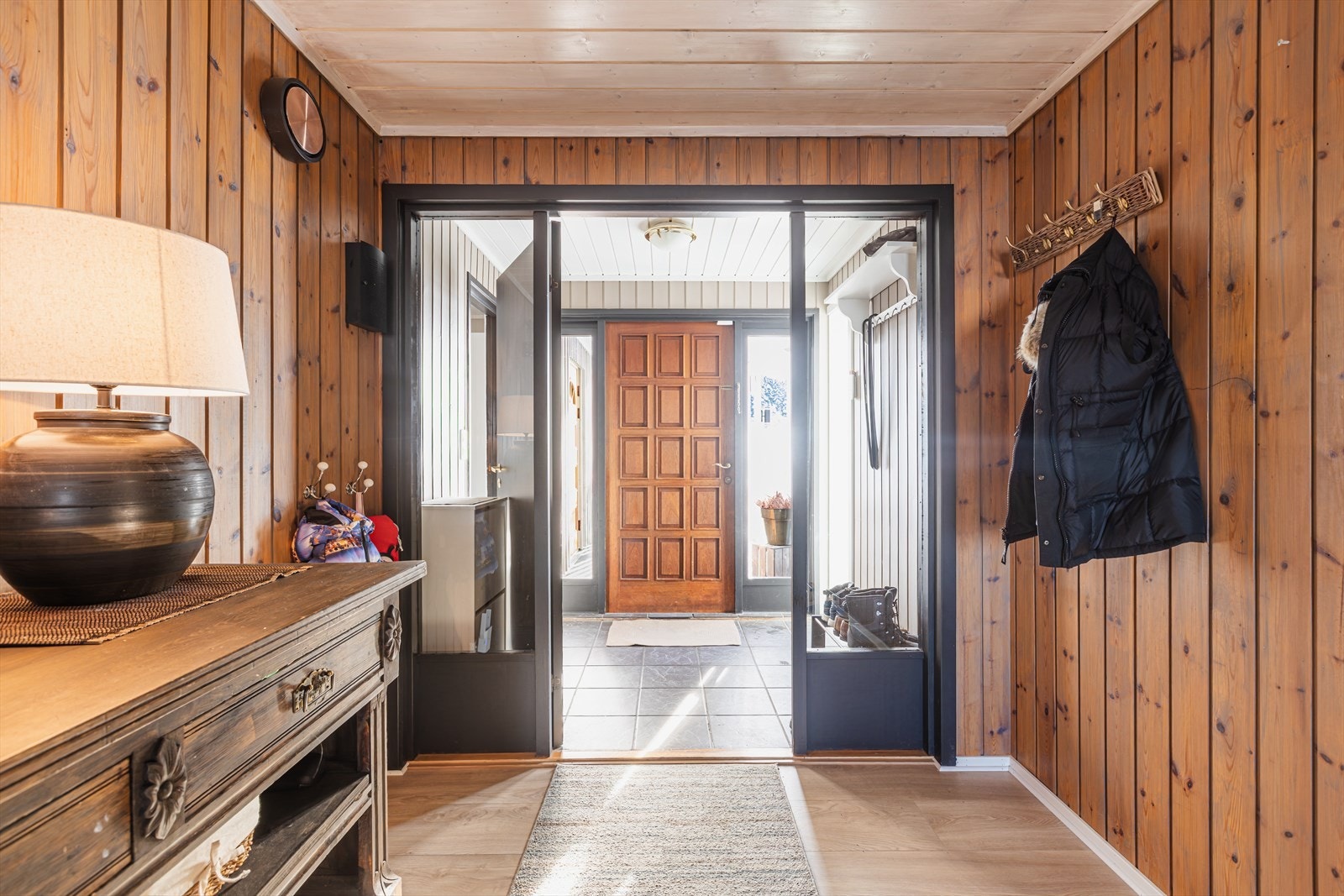 Beiset panel på veggene gir en tradisjonell følelse i entréen. Flislagt gulv ved inngangsdøren gir en praktisk løsning for våte dager. Fra vindfanget er det adkomst til vaskerommet. Galleribilde