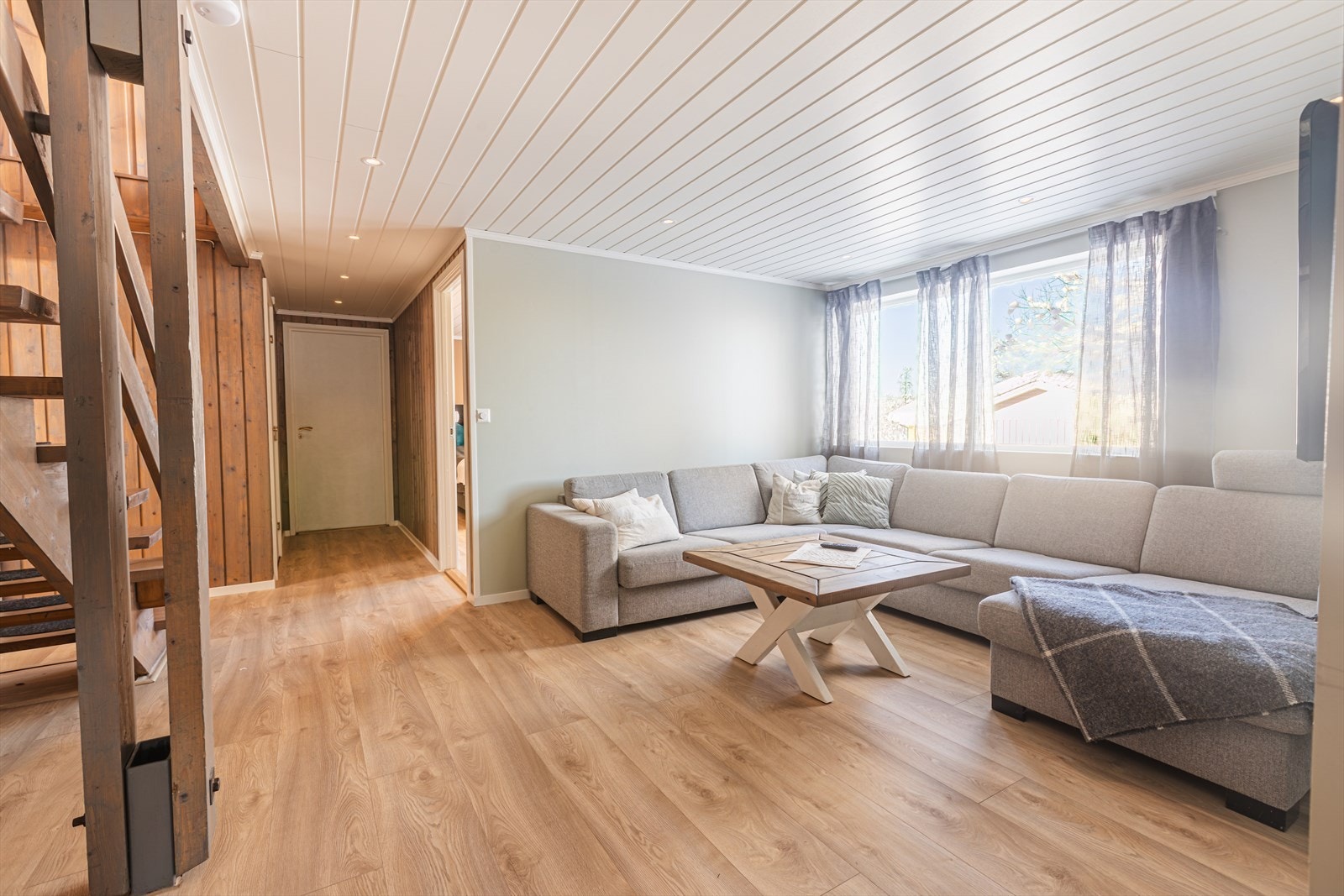 Store vinduer sørger for godt lysinnslipp i stuen, som har parkettgulv og panelte vegger. Galleribilde