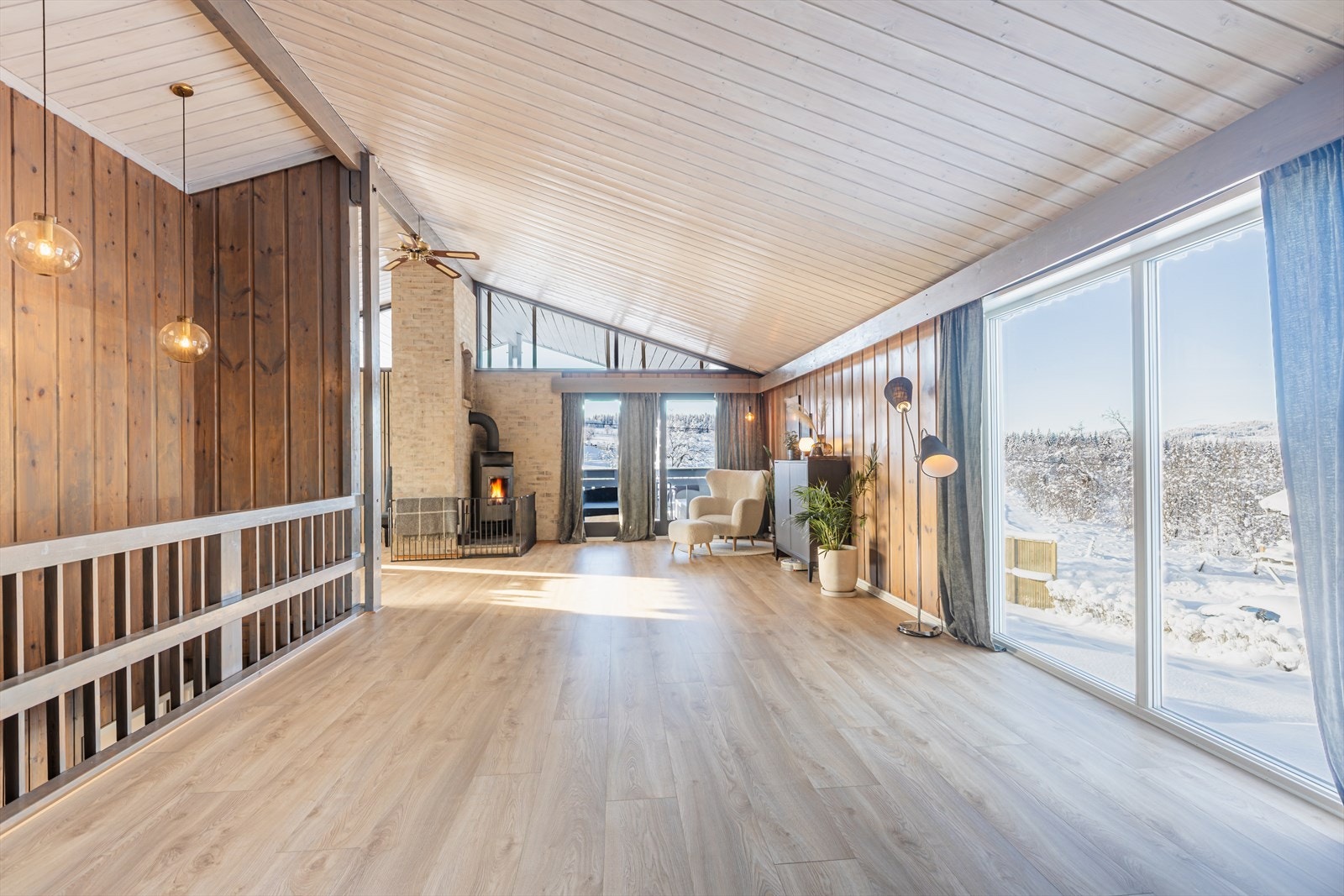 Store vinduer slipper inn rikelig med naturlig lys i stuen som har skråtak og en takhøyde på ca. 3,6 meter Galleribilde