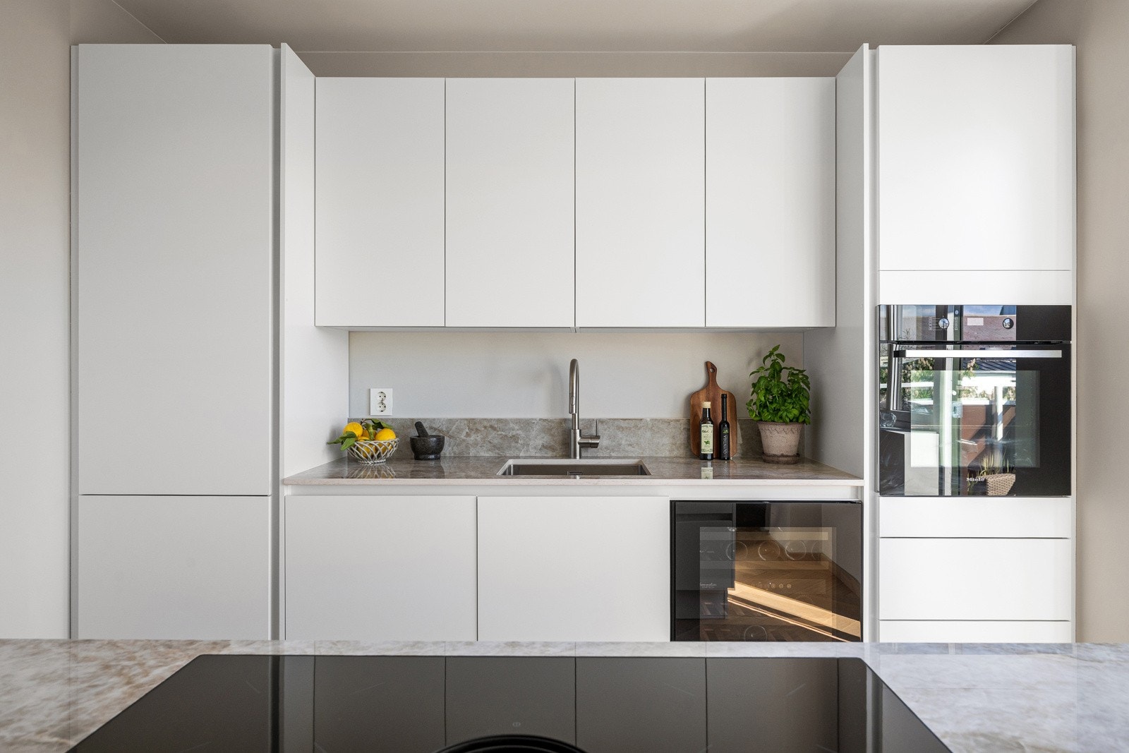 Benkeplater, kjøkkenøy og backsplash er i eksklusive Dekton Arga - et slitesterkt og elegant materiale som gir kjøkkenet et helhetlig og sofistikert uttrykk Galleribilde