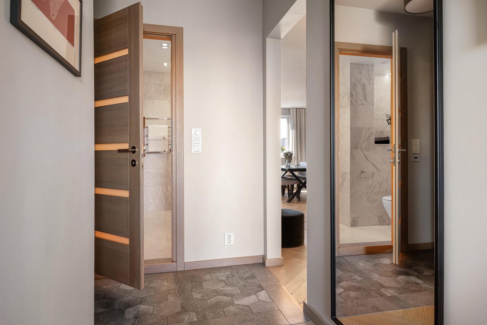 Entreen leder inn til en romslig gang med klassisk fiskebensparkett og plassbygde garderobeskap som gir rikelig med oppbevaringsplass Galleribilde