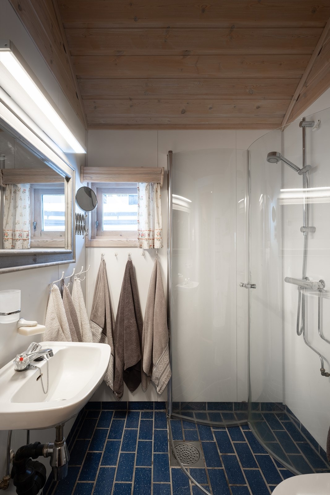 Pent eldre baderom med fliser med varmekabler på gulv. Dusj med innfellbare dusjdører i herdet glass fra 2023. Baderommet har forøvrig servant og gulvstående klosett. Galleribilde