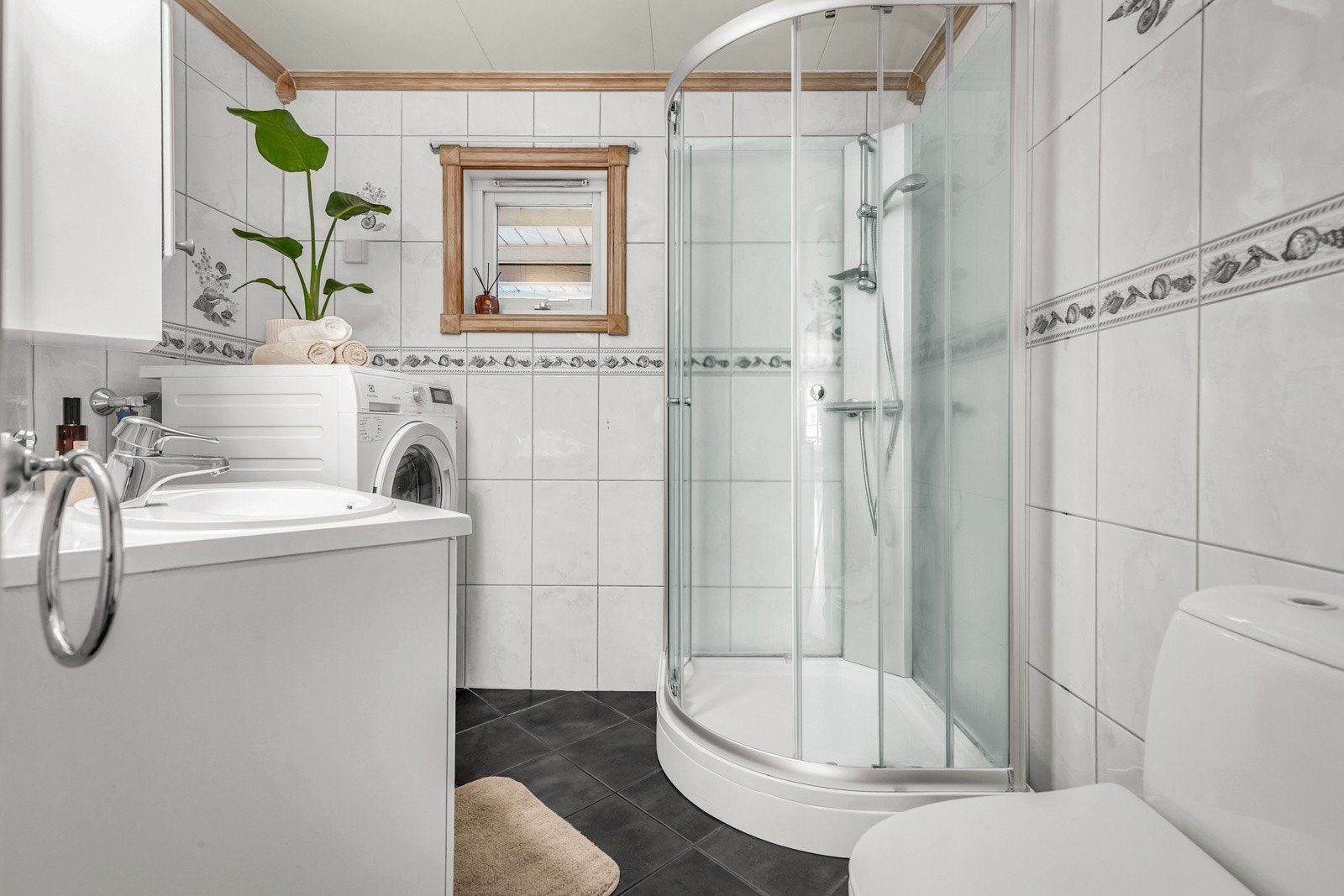 Flislagt gulv med gulvvarme og flislagte vegger. Vegghengt servantinnredning med dører og ovenpåliggende servant. Galleribilde