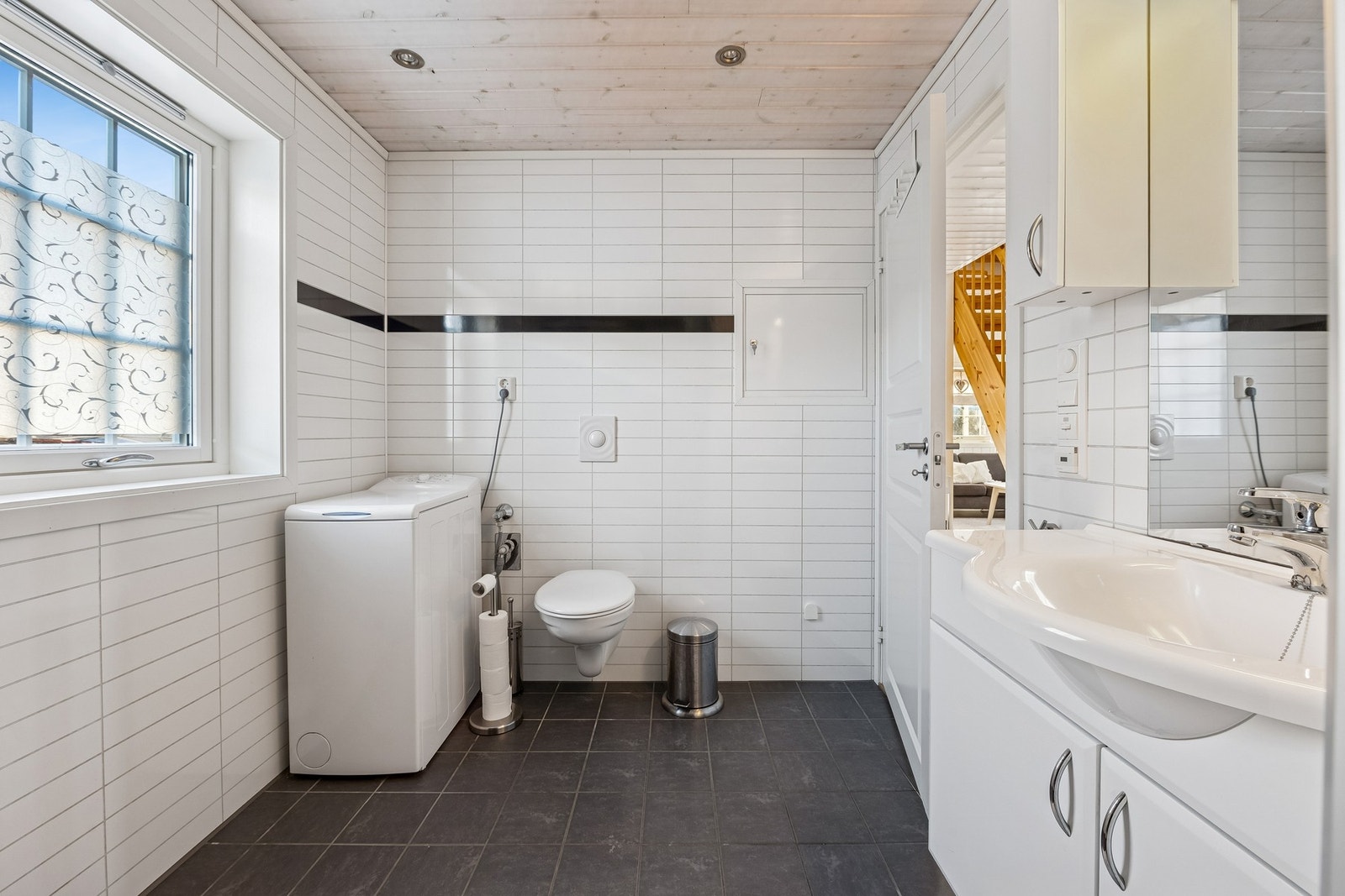 Badet er innredet med veggmontert toalett, dusjkabinett og opplegg for vaskemaskin. Galleribilde