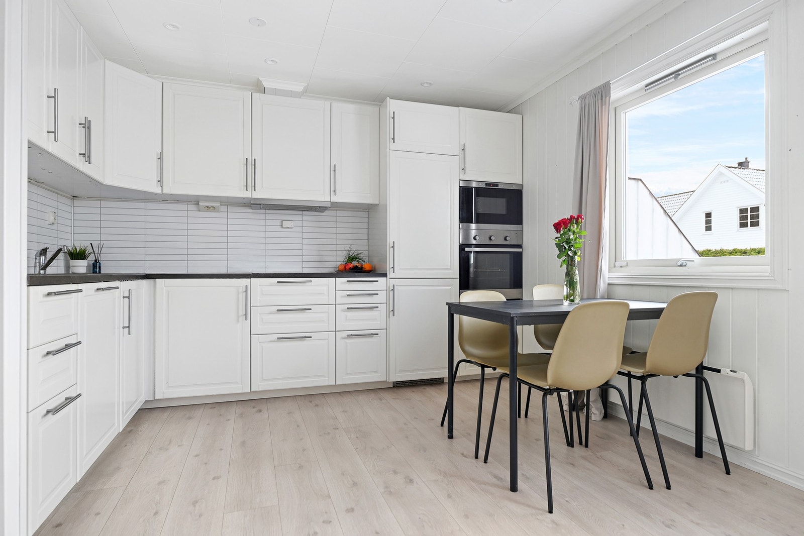 Lyst kjøkken med god benkeplass, integrerte hvitevarer og stort vindu som gir mye naturlig lys. Galleribilde