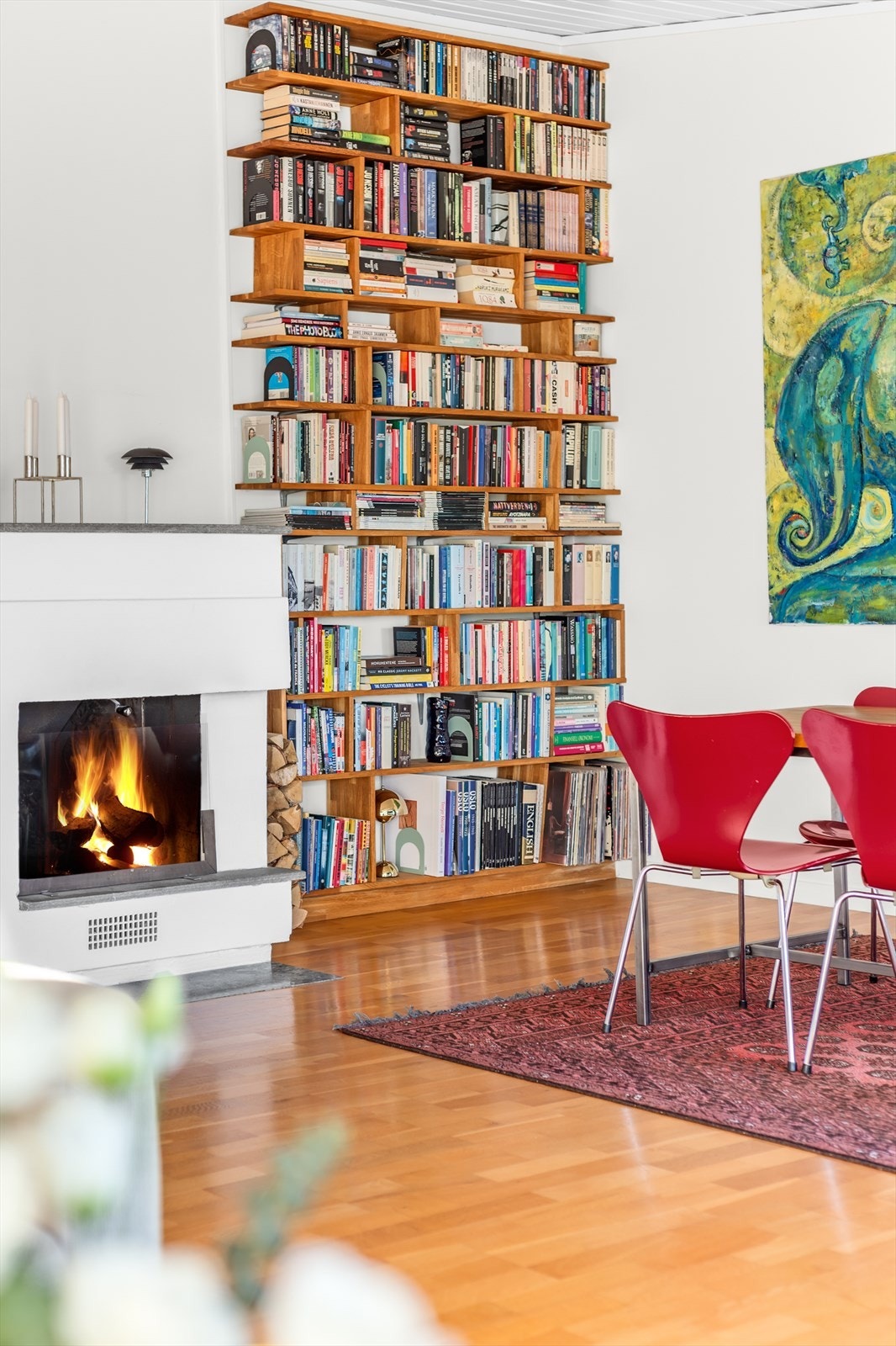 En plassbygd bokhylle utnytter veggen ved peisen på en elegant måte. Galleribilde