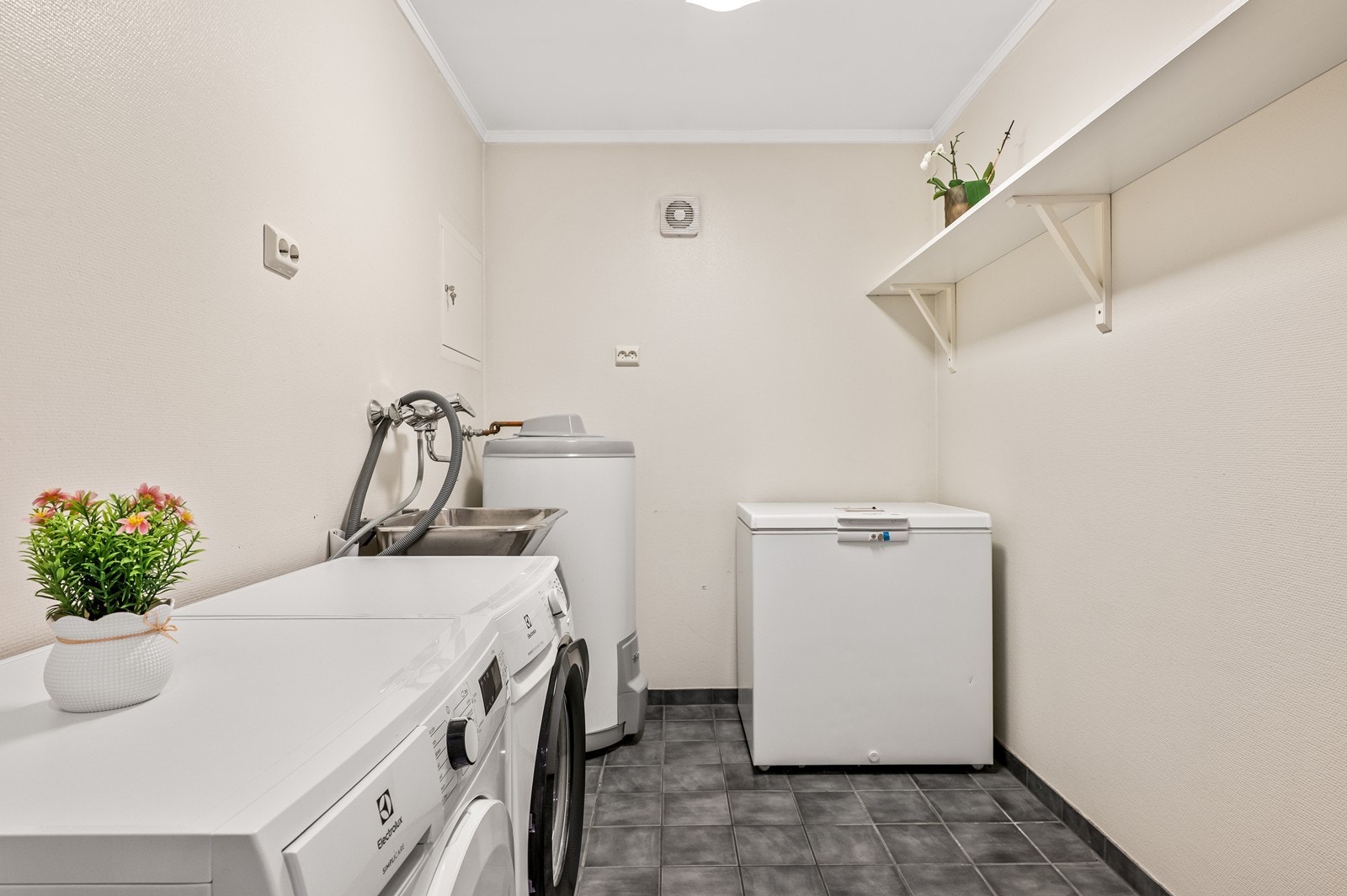 Separat vaskerom med flislagt gulv, utslagsvask og opplegg for vaskemaskin. Galleribilde