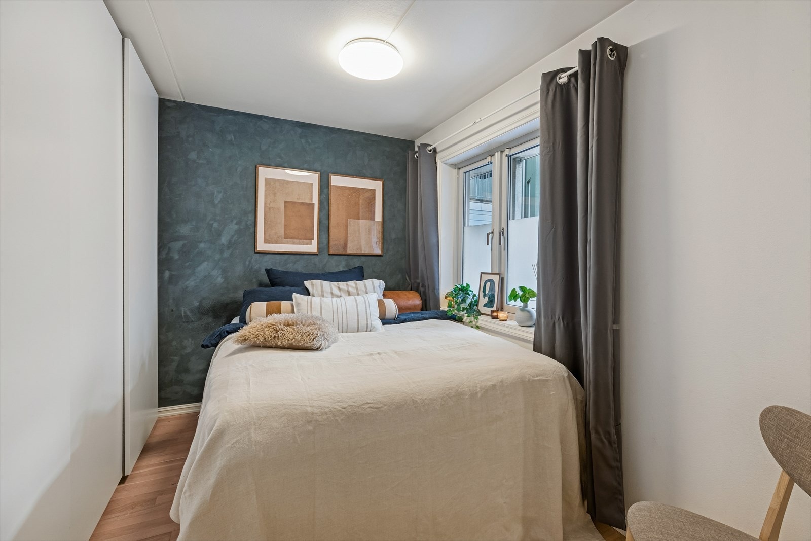 Et lyst og innbydende soverom med plass til dobbeltseng og praktisk garderobeløsning. Rommet vender inn mot en stille bakgård, noe som bidrar til en rolig atmosfære. Galleribilde