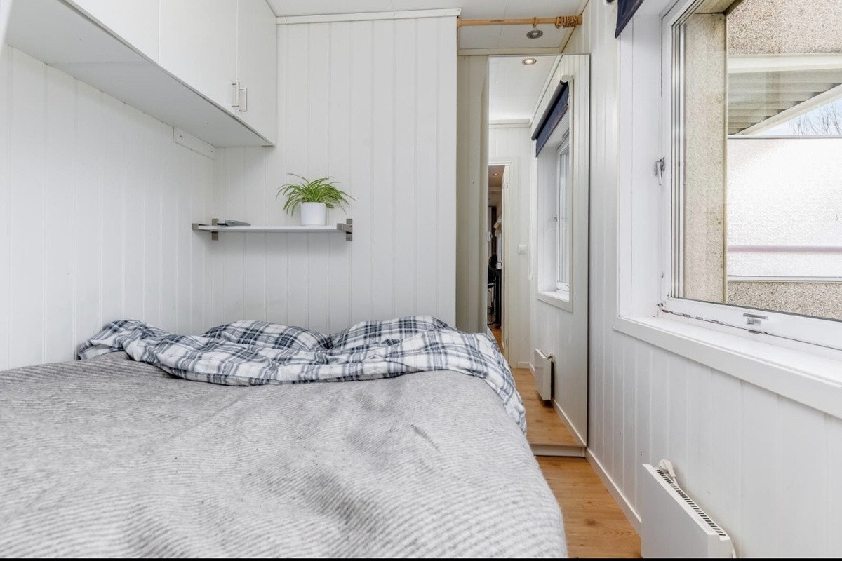 Soverom med stort vindu. Vindu er i senere tid byttet ut med nytt grunnet fasade oppgradering. Garderobeskap over -og ved sien av seng Galleribilde