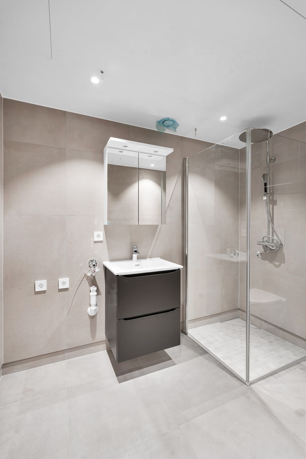 Lekkert, komplett flislagt bad med storformatfliser i behagelige farger. Grå gulvfliser som tilvalg, og beige på vegger. Galleribilde