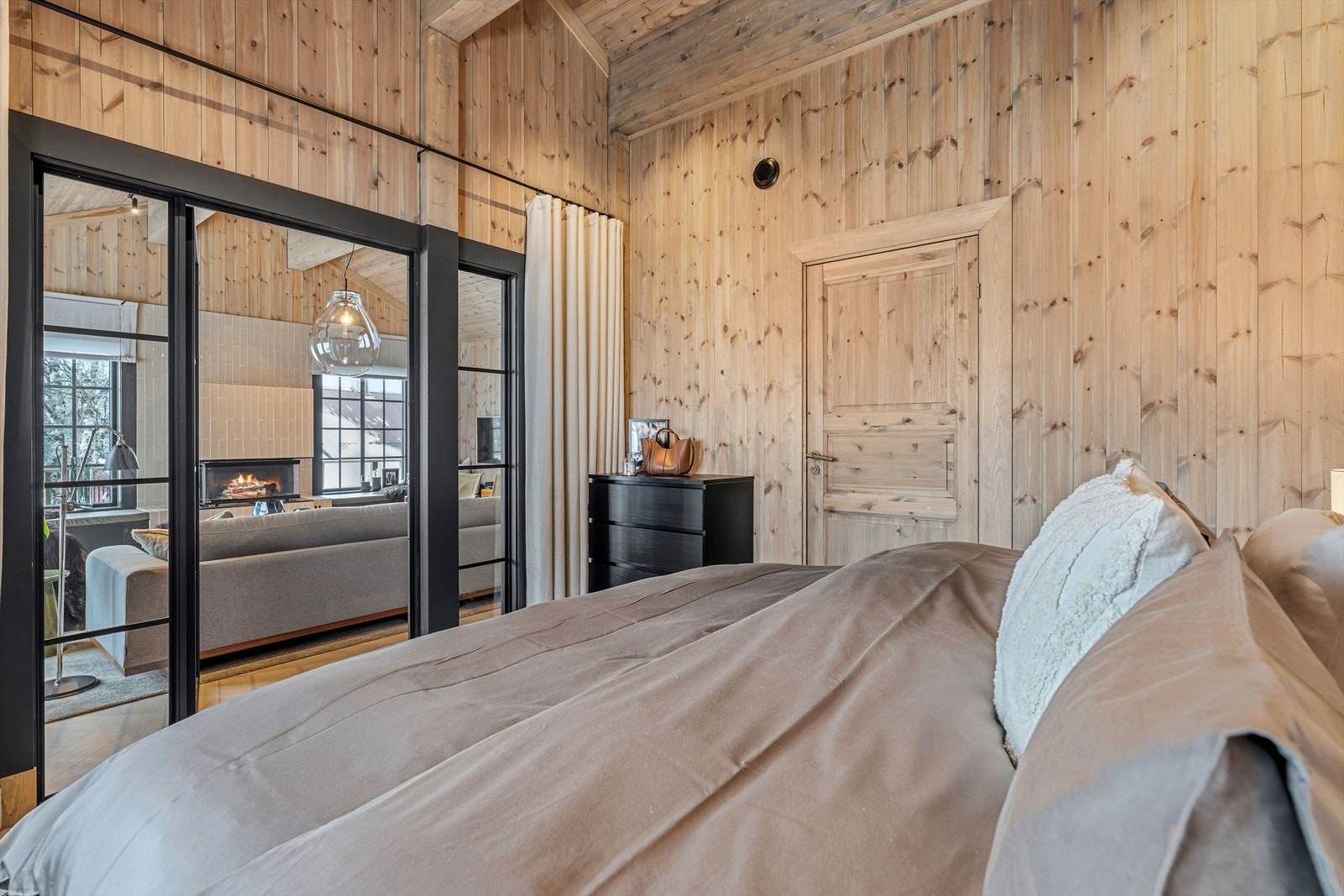 Fra sengen ser du ut mot natur og peis gjennom delikate glassdører. Galleribilde