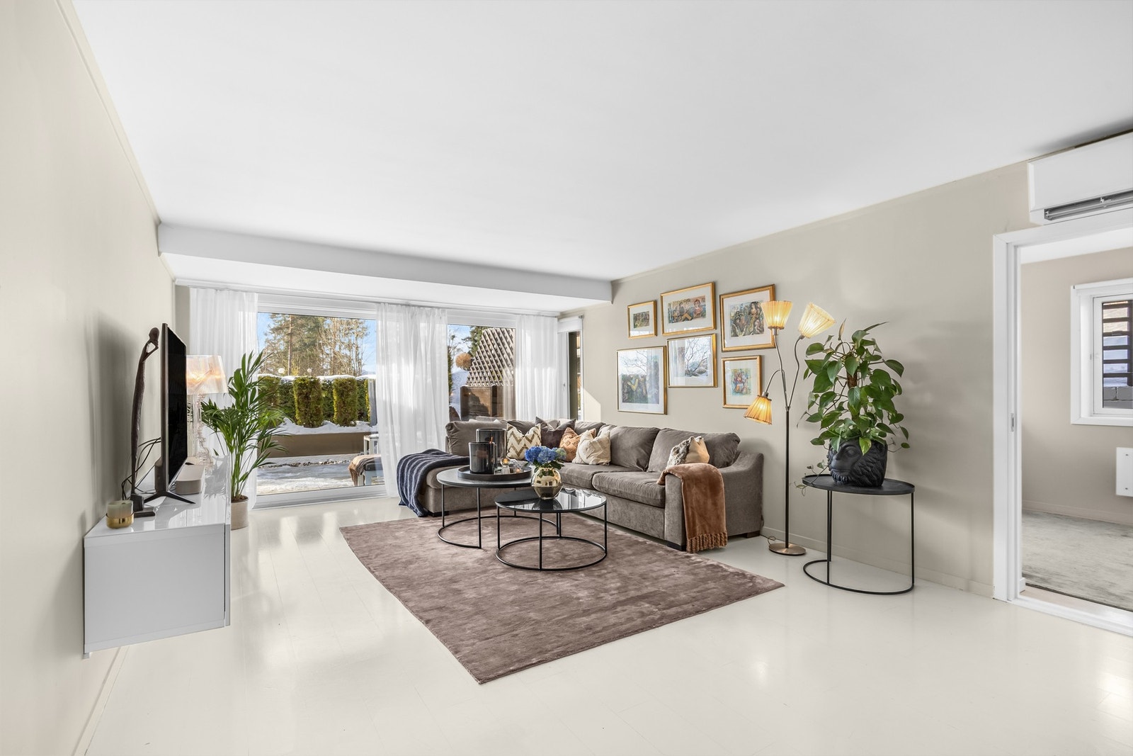 Lys, inviterende og stor stue hvor takhøye vindusflater slipper inn godt med sollys. Det er utgang til vestvendt markterrasse med frodige grøntarealer i front Galleribilde