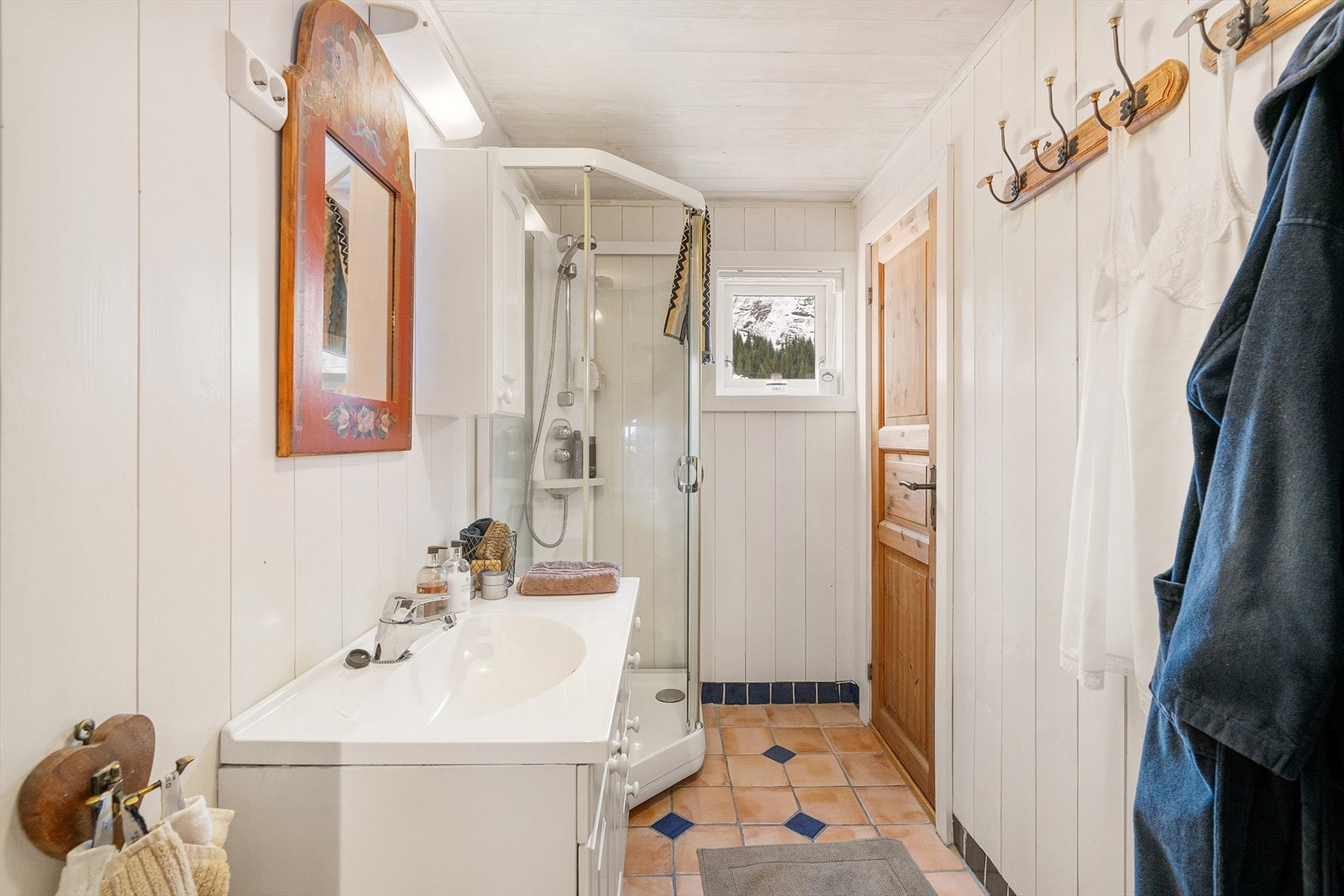 Ett av badene - her med dusjkabinett. Vindu for naturlig lys, og god oppbevaring i seksjon. Eget toalett inn til høyre. Galleribilde