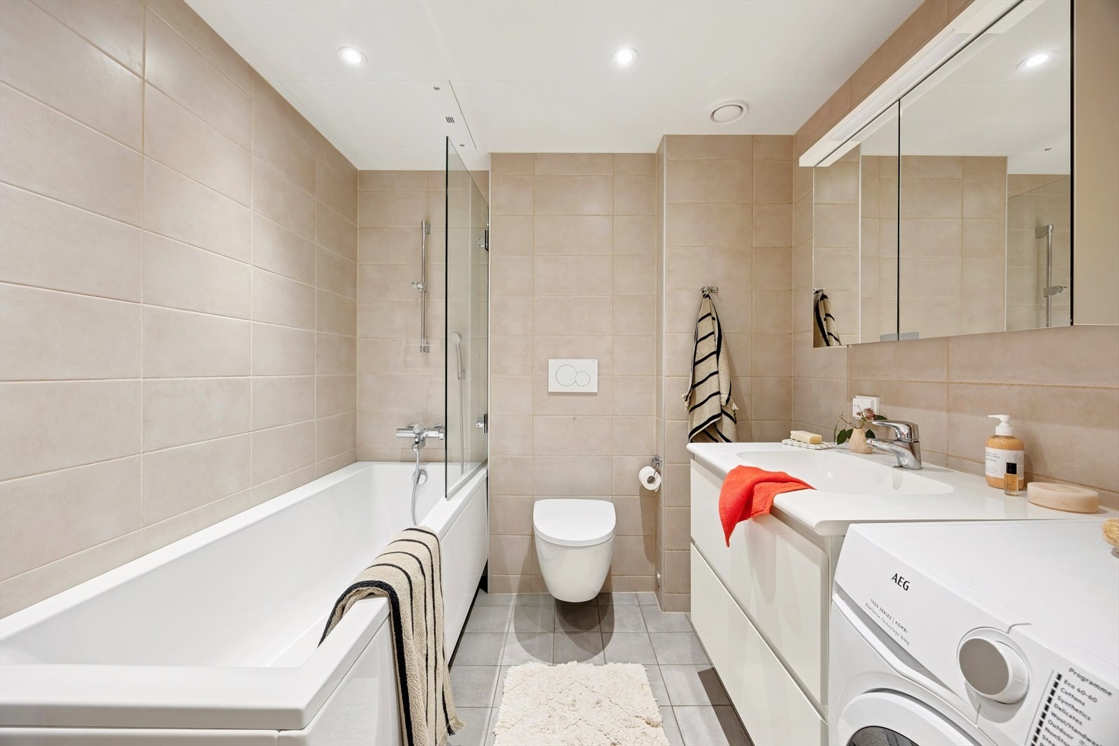 Innredning bestående av servantskap i hvit glatt utførelse med heldekkende servant, speildel med skap, vegghengt wc og badekar. Det er opplegg og plass for vaskemaskin. Galleribilde