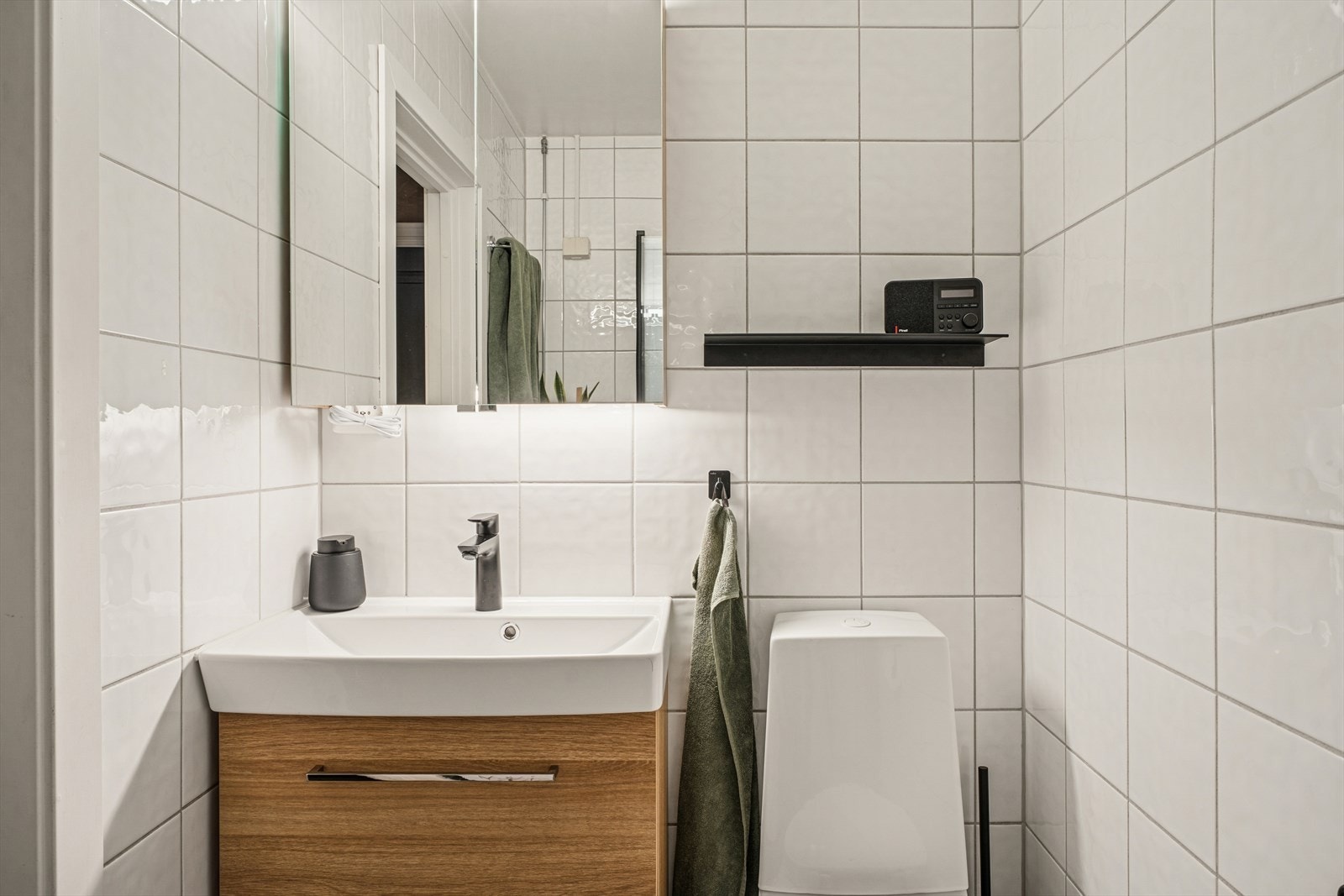 Innredning og garnityr på bad fremstår med: WC, dusjplass med inn-utadslående dusjvegger, servant med ettgreps blandebatteri i innredning og opplegg for vaskemaskin Galleribilde