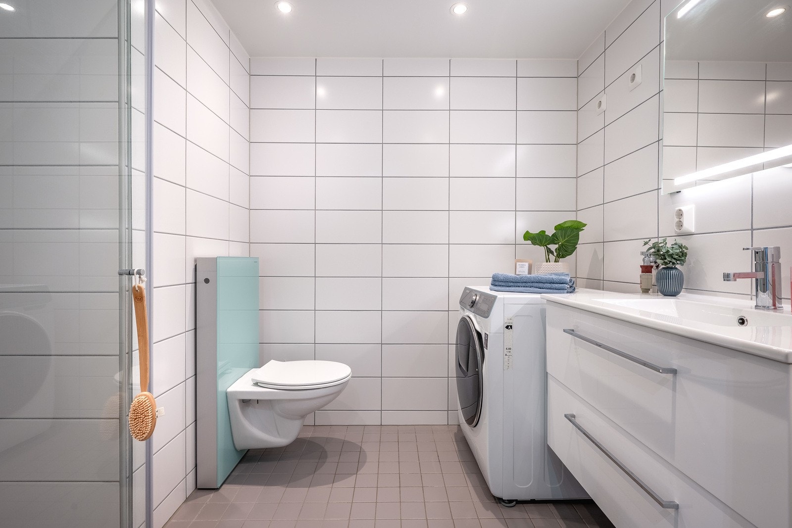 Moderne, flislagt bad med elektriske varmekabler i gulvet og opplegg for vaskemaskin. Galleribilde