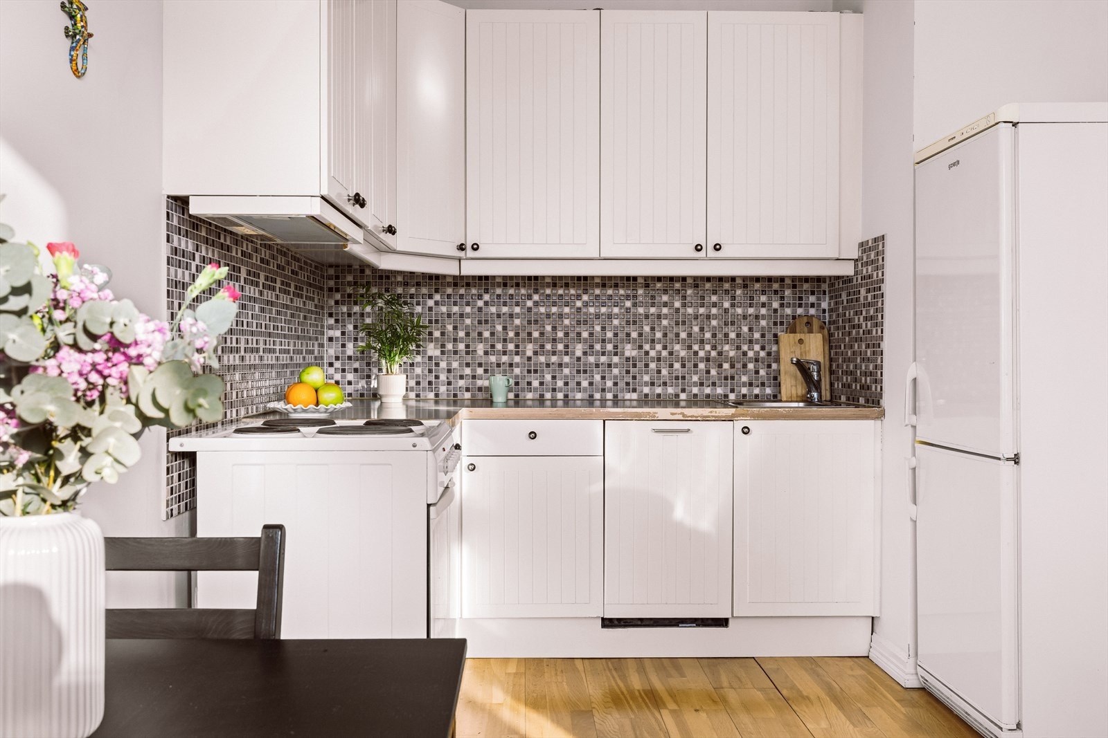 Kjøkken fra 2006 med hvite fronter og laminert benkeplate. Galleribilde