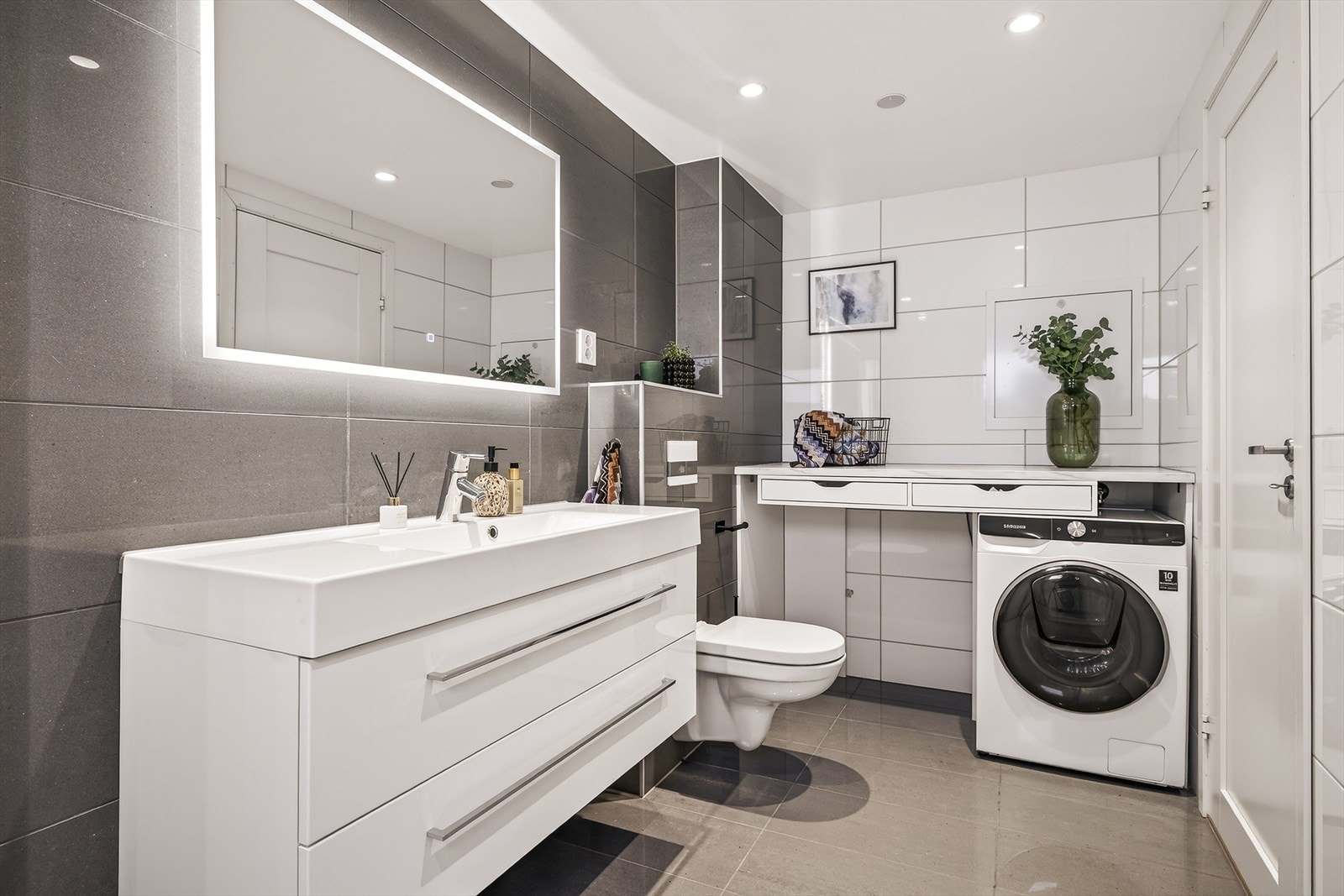 Badet har god plass, flislagte overflater og integrert belysning. Galleribilde