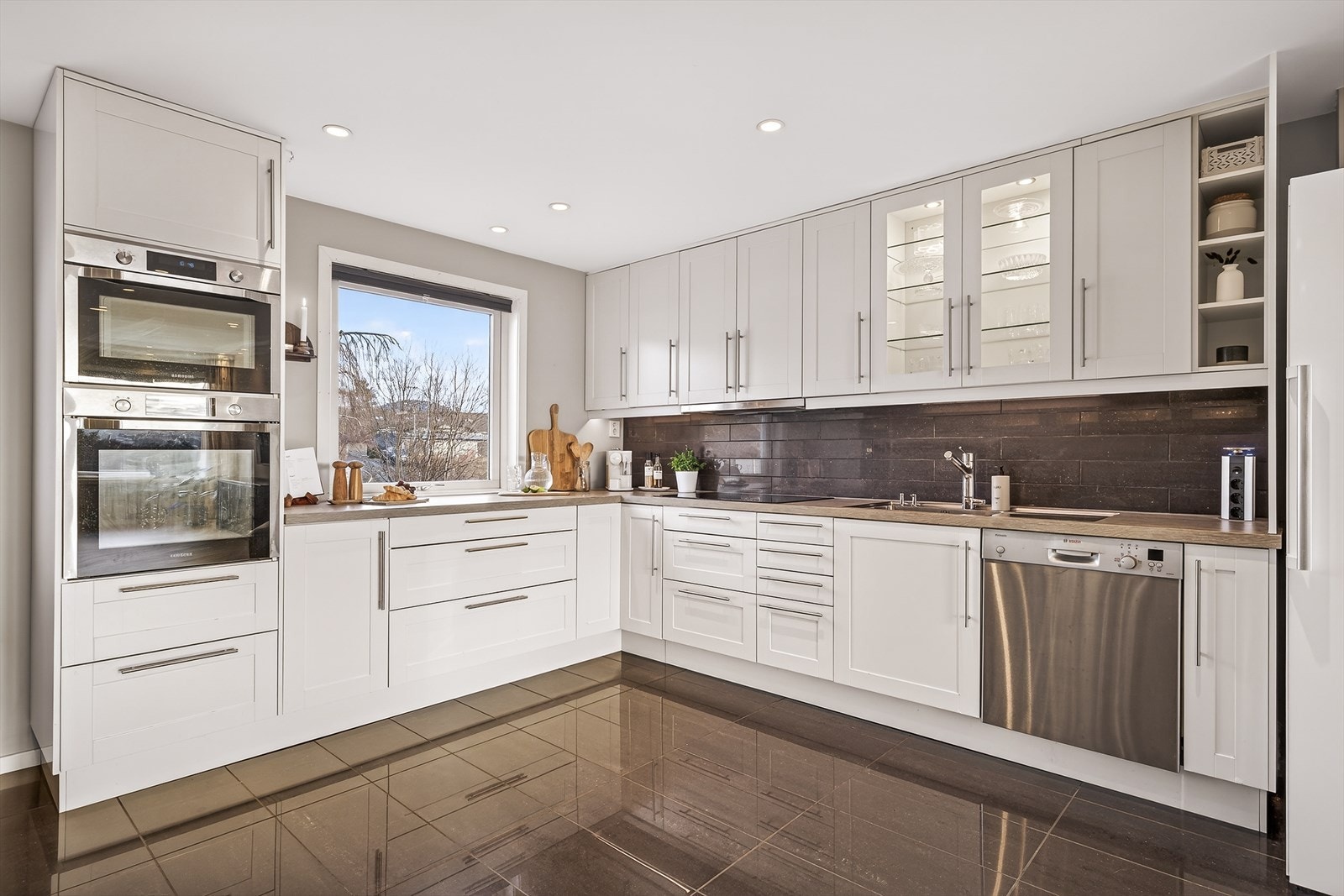 Oversiktlig og moderne kjøkkenløsning med integrert ovn, induksjonstopp og smart oppbevaring. Galleribilde