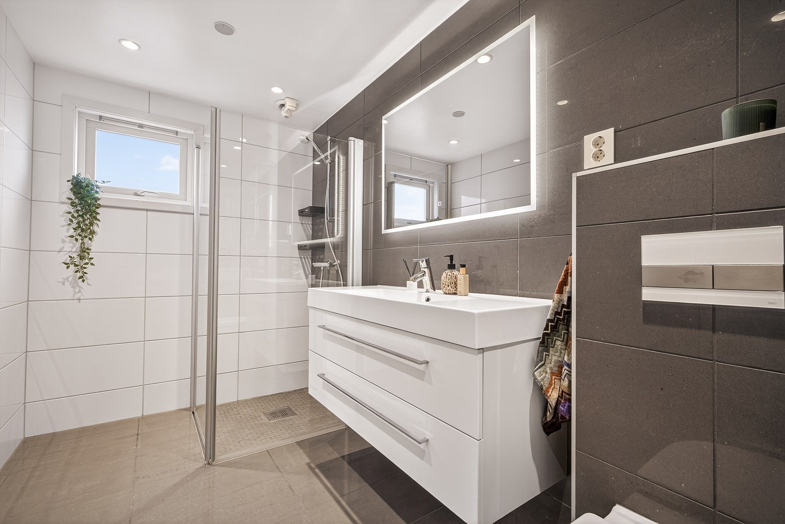 Helfliset bad med dusjsone, vegghengt toalett og moderne innredning. Galleribilde