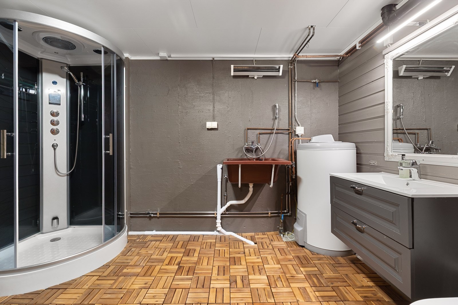 Bad/vaskerom. Det er i nyere tid blitt montert dusjkabinett, gulvstående toalett,
innredning med heldekkende servant, stråleovn på vegg og nyere
varmtvannstank. Varmtvannstanken er på ca. 200 liter Galleribilde