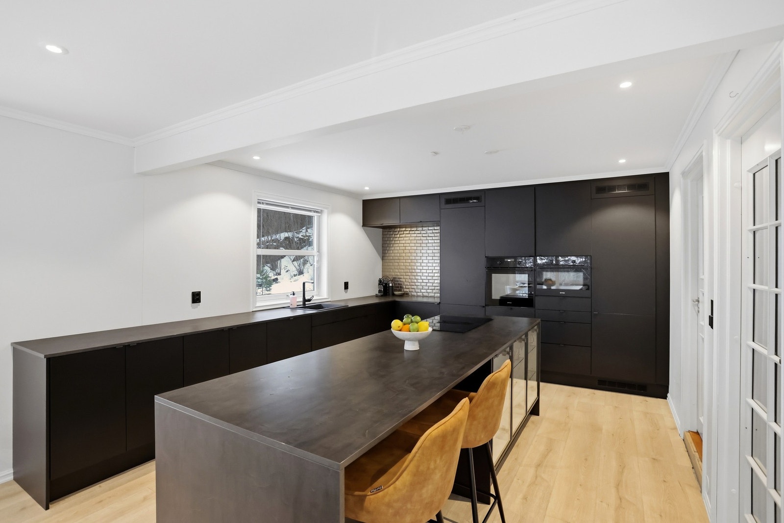 Tidsriktig og fin kjøkkeninnredning fra Systemkjøkken, med integrerte hvitevarer, laminat benkeplate og stor kjøkkenøy. Innredningen er fra 2021. Galleribilde