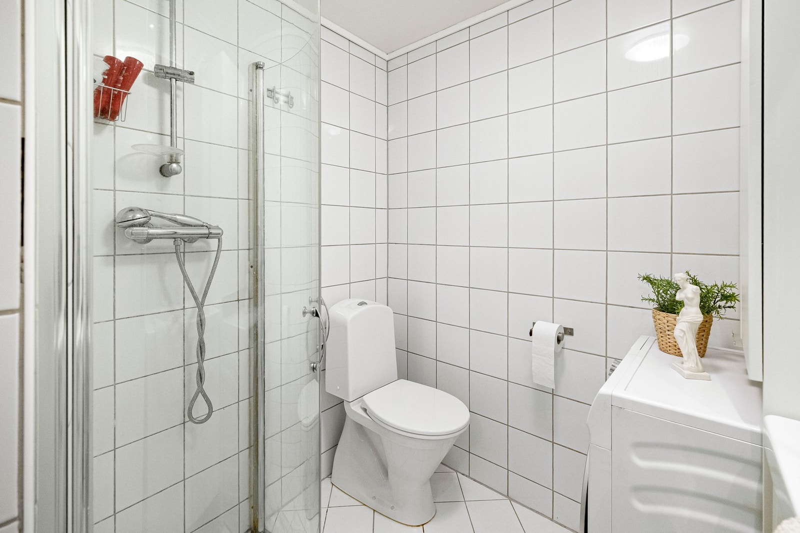 Badet har en lys og tiltalende utforming med hvite fliser på både vegger og gulv. Galleribilde