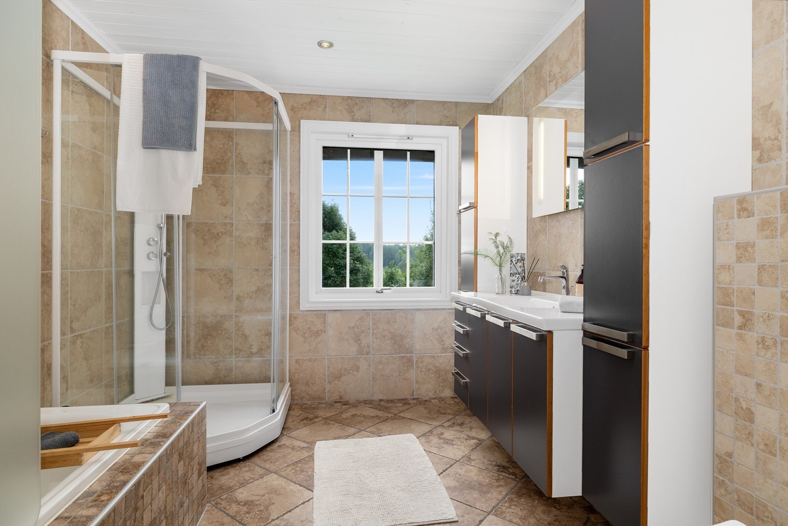 Badet i hovedetasjen er helflist, her har man badekar, dusjkabinett og servantskap med speil over Galleribilde