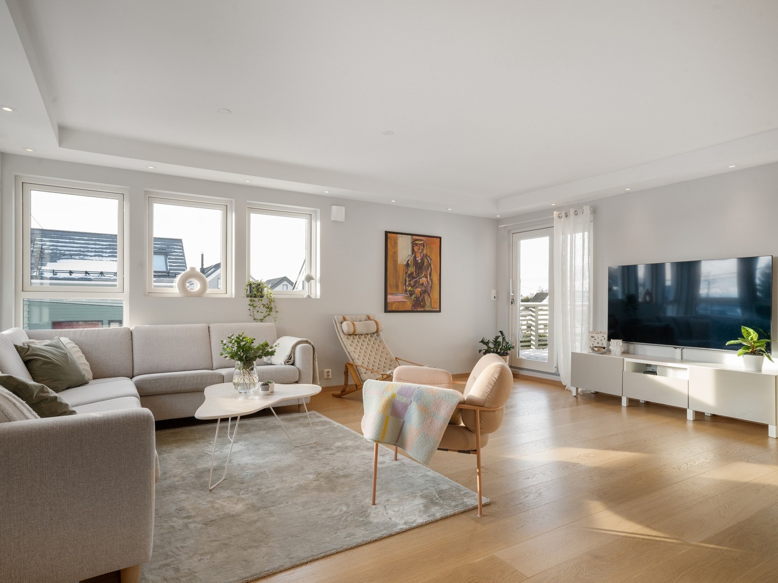 En romslig stue med vinduer i flere retninger som gir innslipp av mye dagslys. Galleribilde