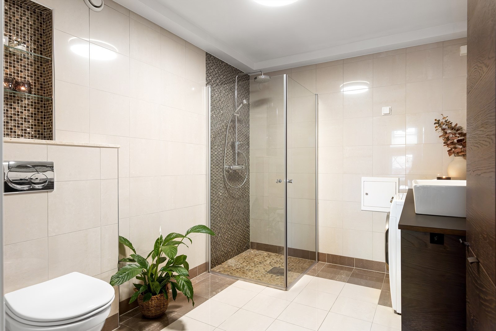 Badet består servantskap med topp servant, veggskap med speildører, speil med berøringslys, vegghengt klosett og dusjsone med innfelte dusjdører i herdet glass. Det er opplegg vaskemaskin. Galleribilde