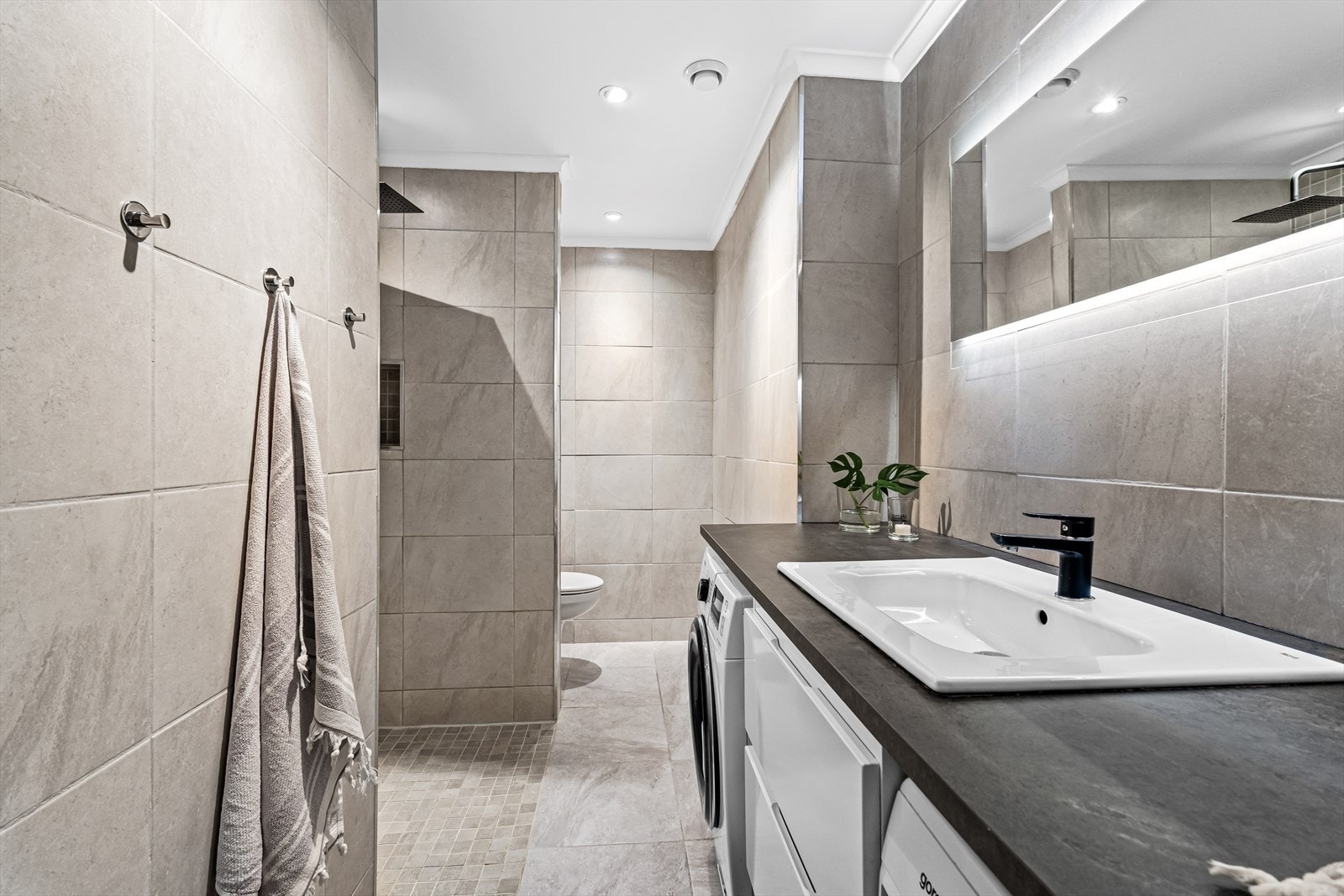 Delikat og stort bad renovert i 2019 - Pent flislagt bad, stor dusjnisje, vegghengt wc, praktisk opplegg for vaskemaskin og tørketrommel. Galleribilde