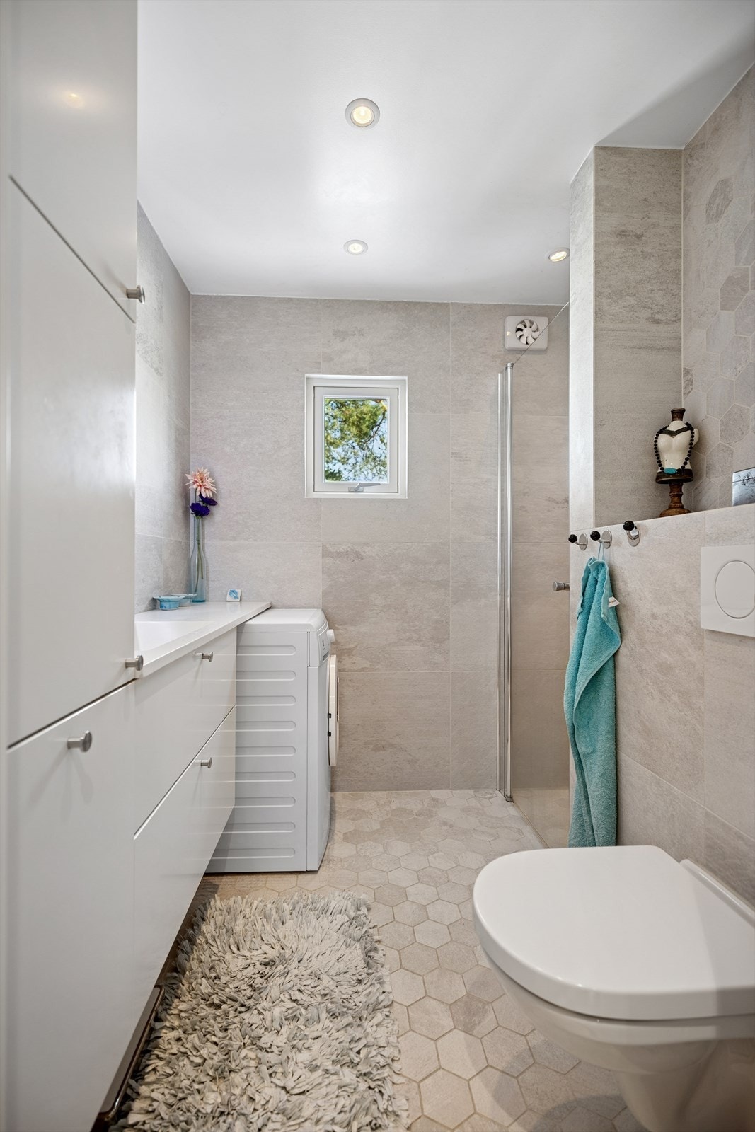 Gulvet har grå, sekskantede fliser, og veggene har grå fliser som gir et moderne uttrykk. Galleribilde