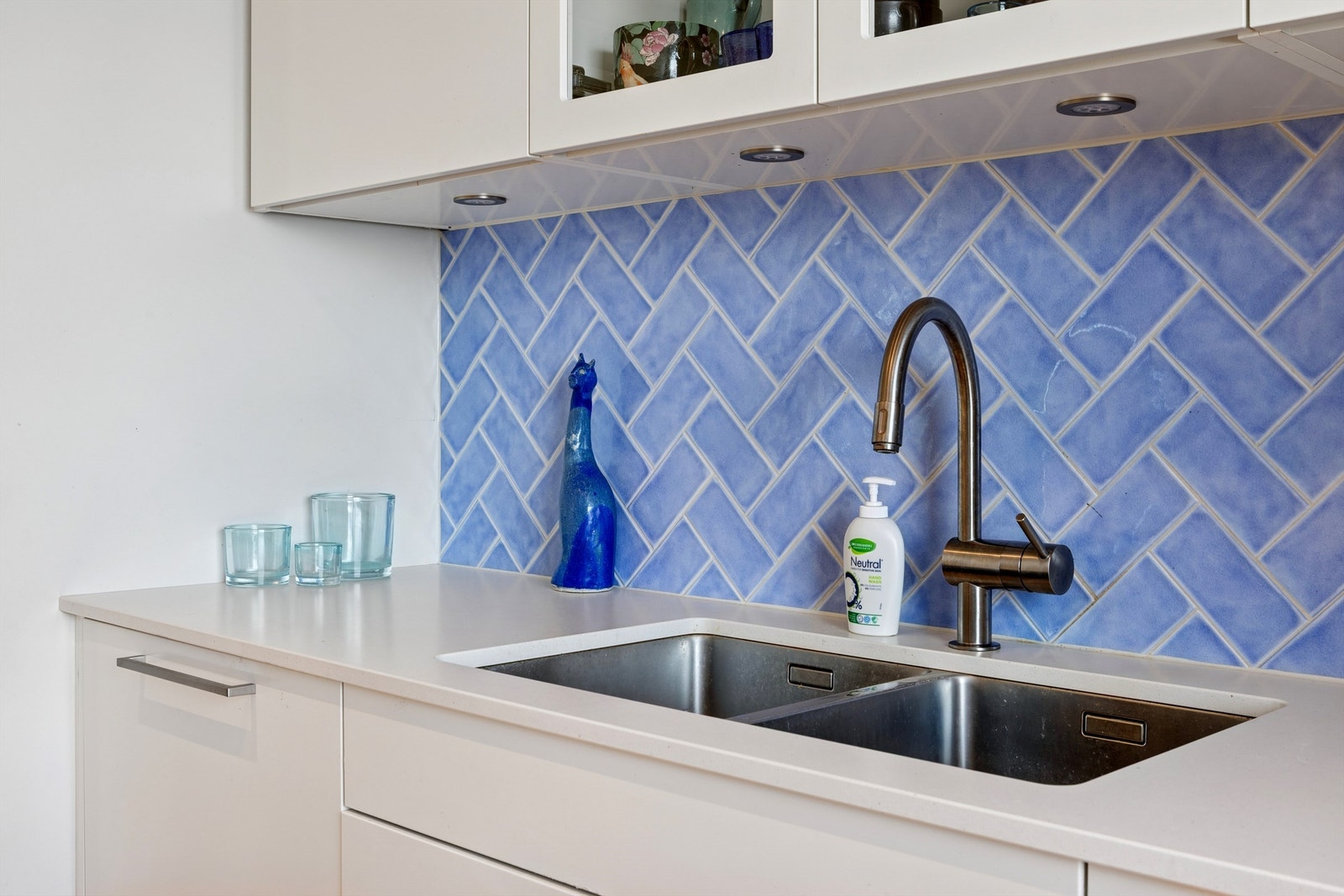 Kompositt benkeplate med underlimt dobbel oppvaskkum, og delikate blå fliser som gir kjøkkenet et moderne uttrykk Galleribilde