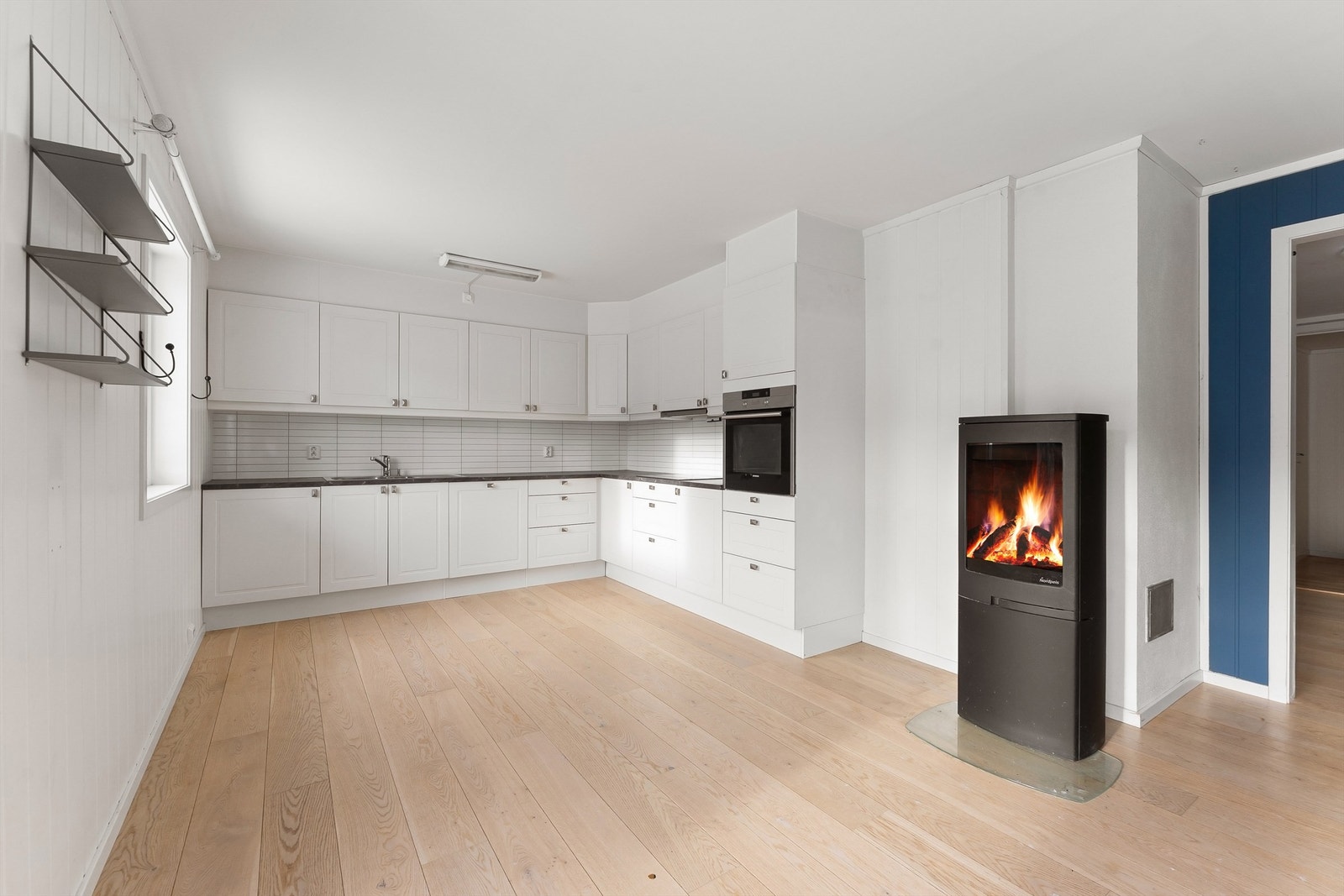 Kjøkkenet er plassert i åpen løsning mot stuen, med peisovnen som et sentralt element. Galleribilde