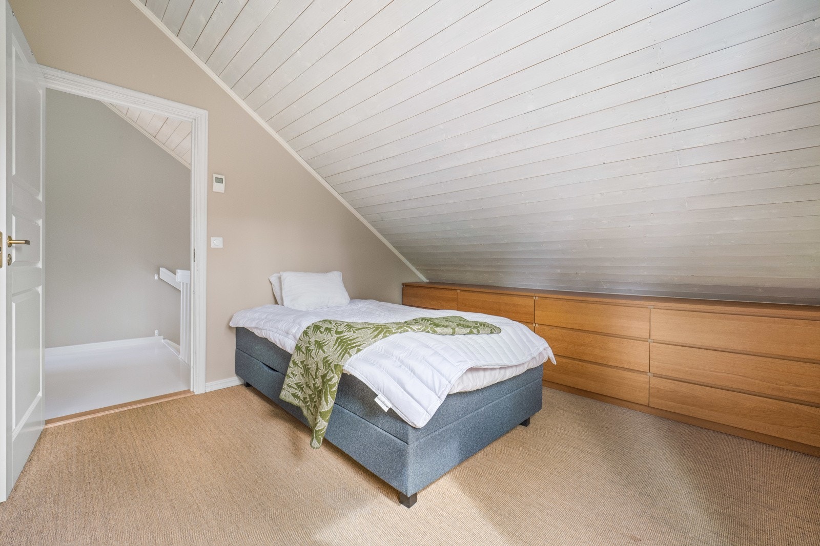 Andre etasje byr på tre gode soverom, alle med lune tepper på gulv, skråtak i panel og malte, glatte vegger. Galleribilde