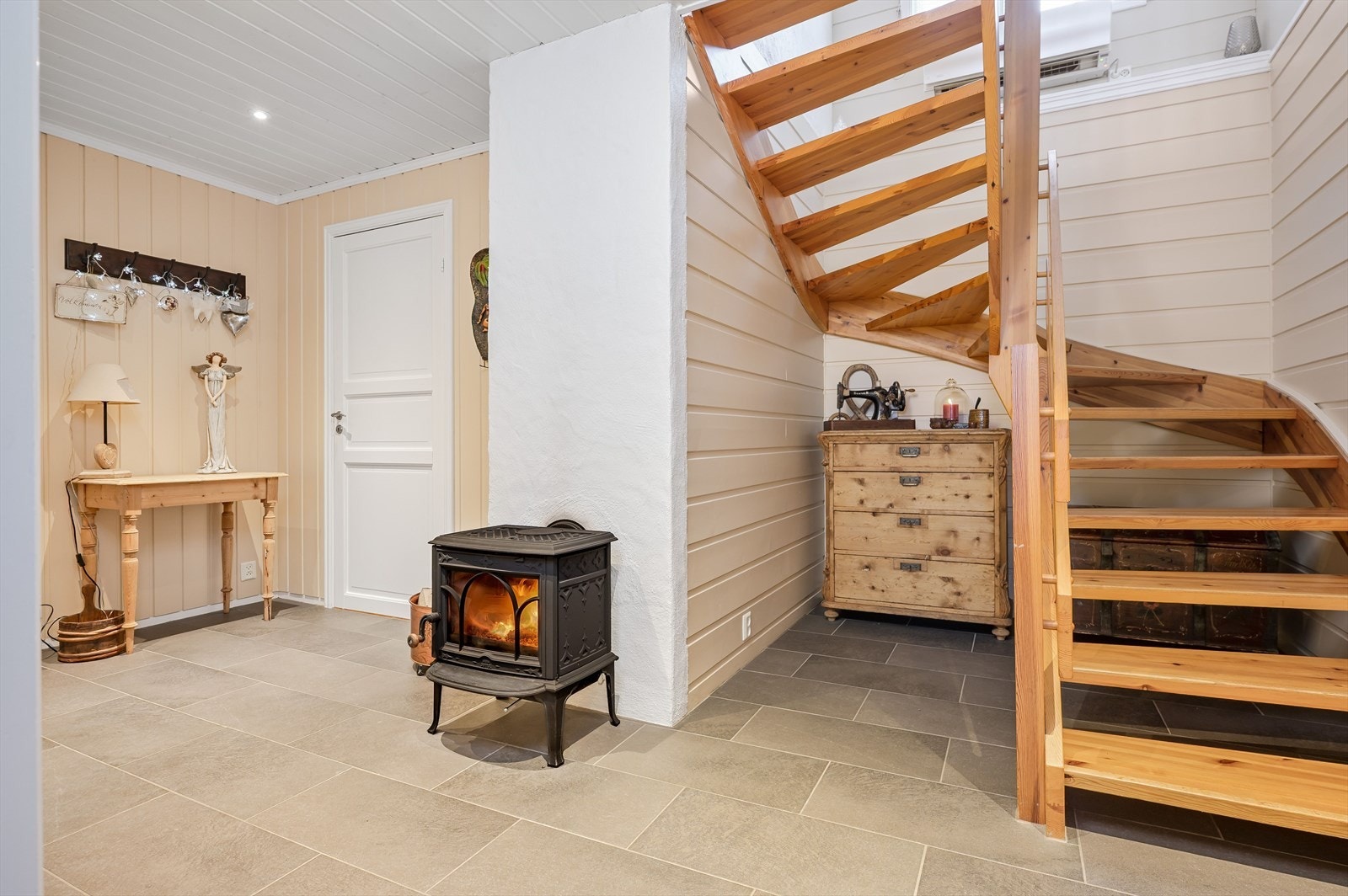 Videre kommer du inn til gang/trapperom med flislagt gulv, downlights i himlingen og en koselig vedovn. Det er også montert luft-til-luft varmepumpe i trappen som sørger for en god og jevn varme på vinterstid. Galleribilde