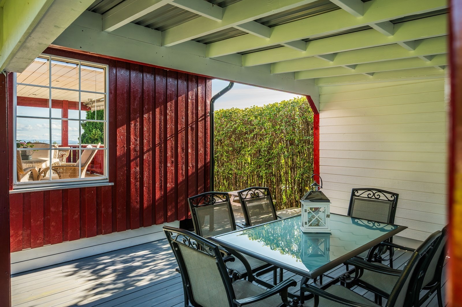I bakkant av terrassen er det en koselig overbygget uteplass med terrassebord på gulv. Galleribilde