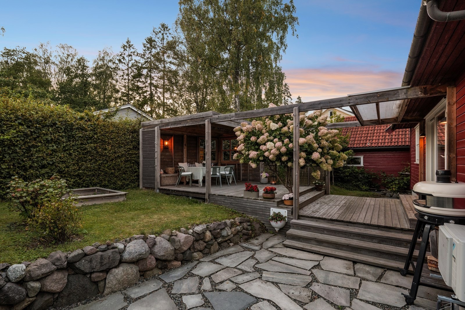 Tomten er pent opparbeidet med plen, beplantning og steinlagte partier. Galleribilde