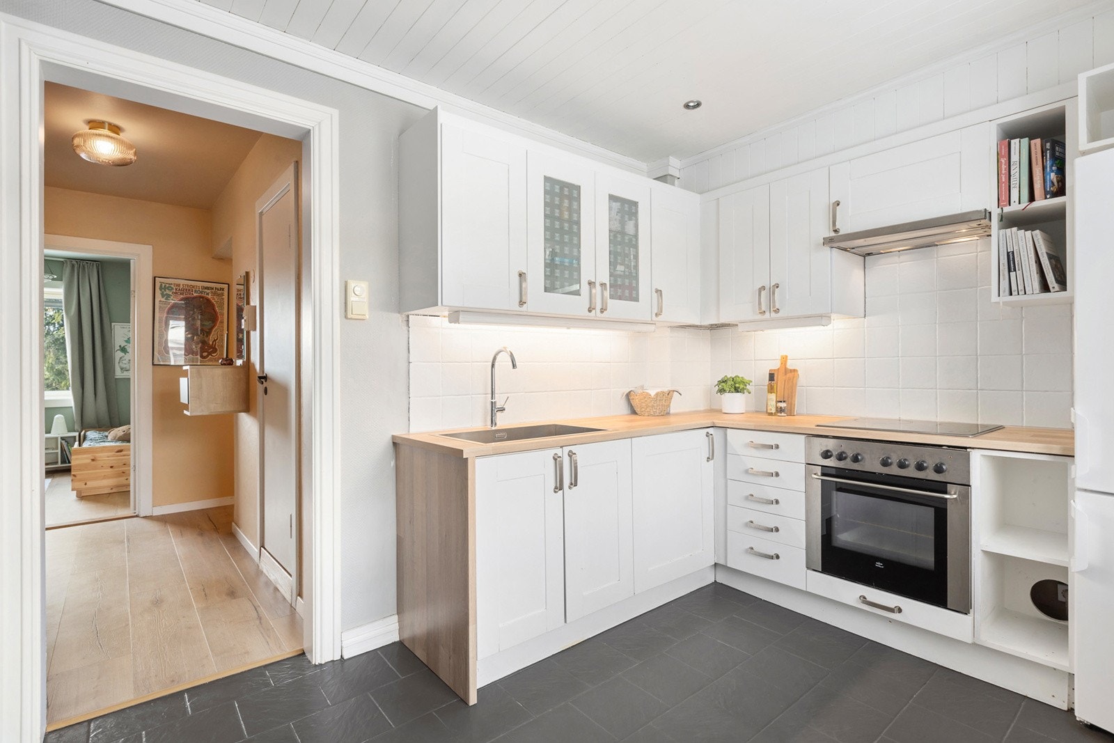 IKEA kjøkkeninnredning med et-speils malte skapfronter, laminat benkeplate, enkel oppvaskkum, ventilator og hvitevarer som koketopp,stekeovn samt frittstående kjø/-fryseskap. Galleribilde