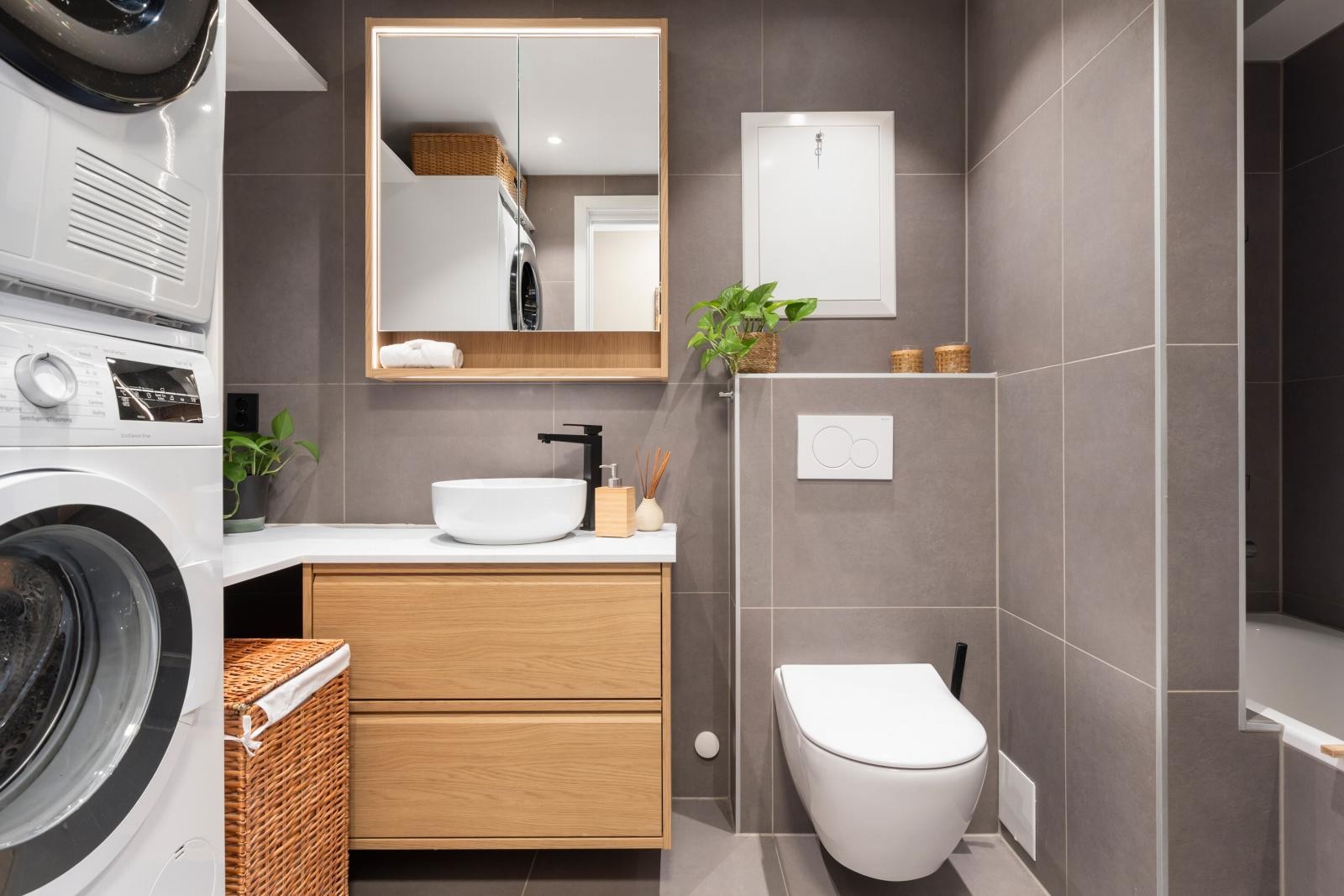 Moderne flislagt bad fra 2024 med opplegg for vaskemaskin. Galleribilde